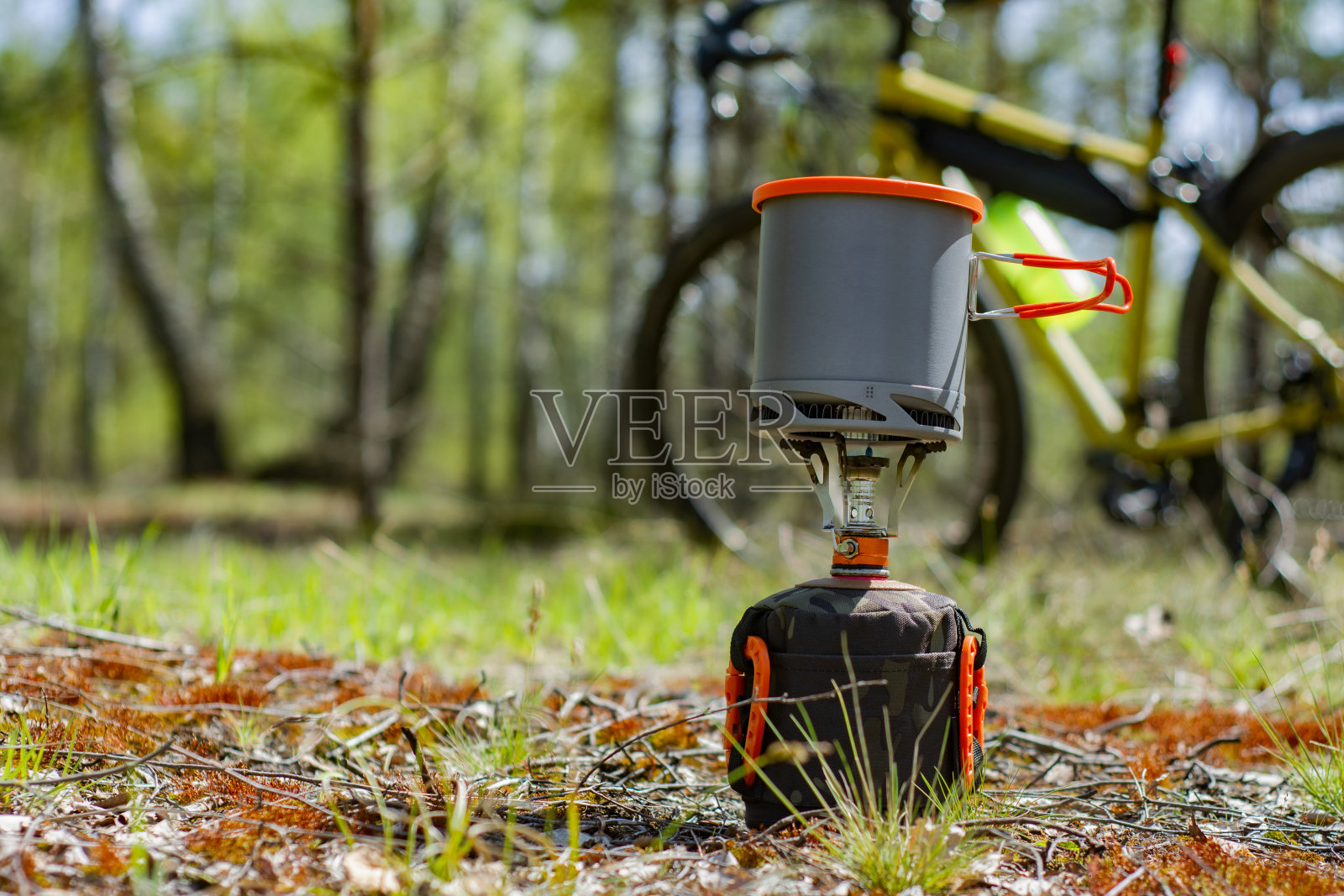露天露营，背景是一辆自行车和一片森林。旅游用煤气炉和烹饪锅。照片摄影图片
