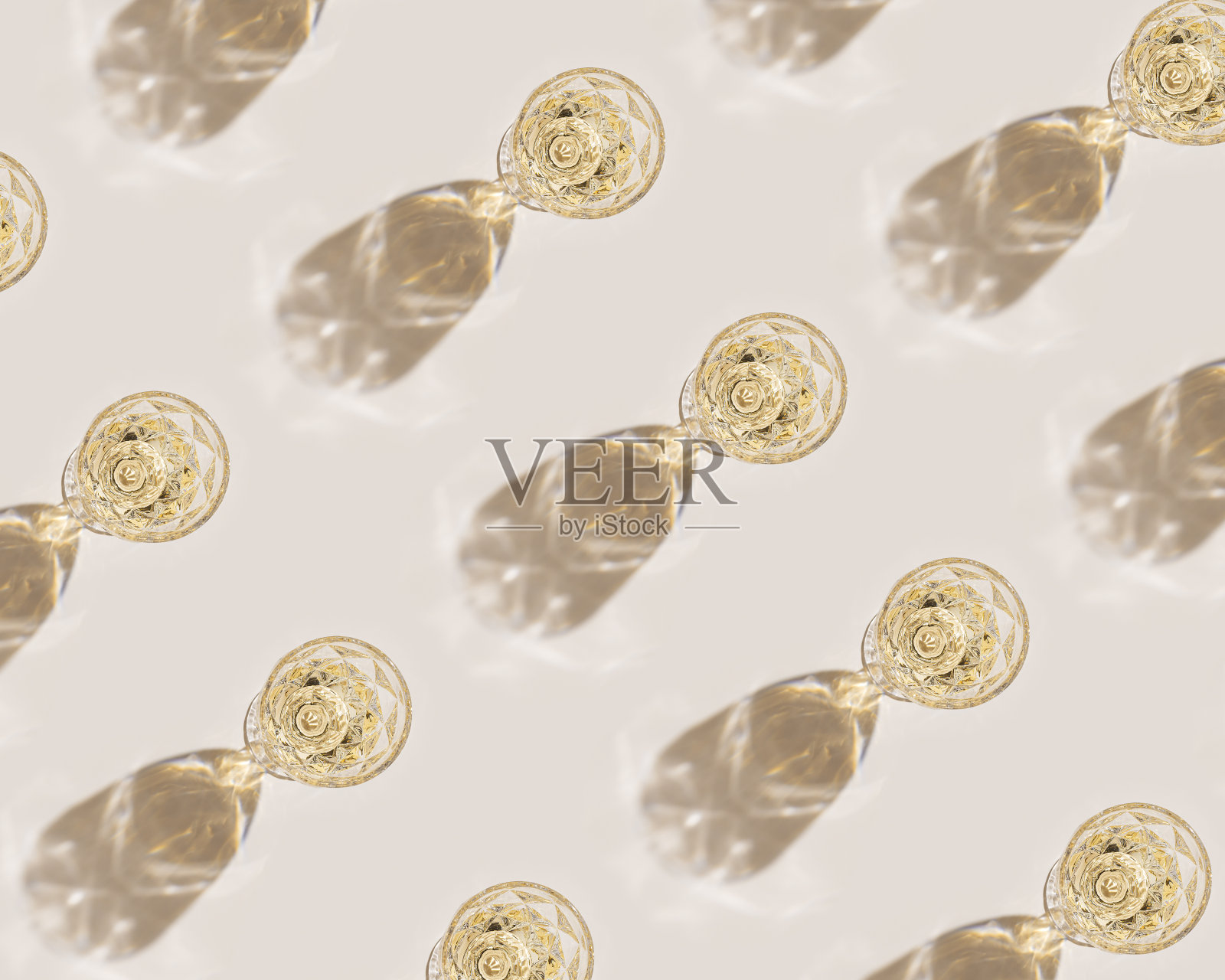 白葡萄酒装在晶莹透明的时尚玻璃杯里，搭配阳光，极简的潮流图案，浅米色背景，创意夏日休息酒饮概念，单色顶景，壁纸照片摄影图片