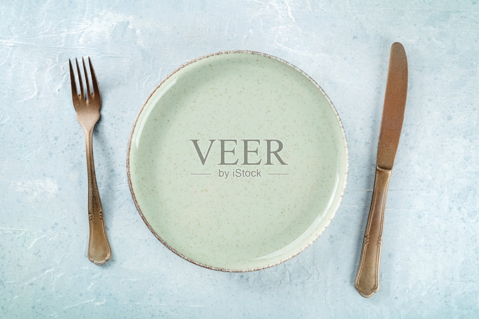 一个空的绿色盘子，上面放着一把刀叉，平躺在头顶上照片摄影图片