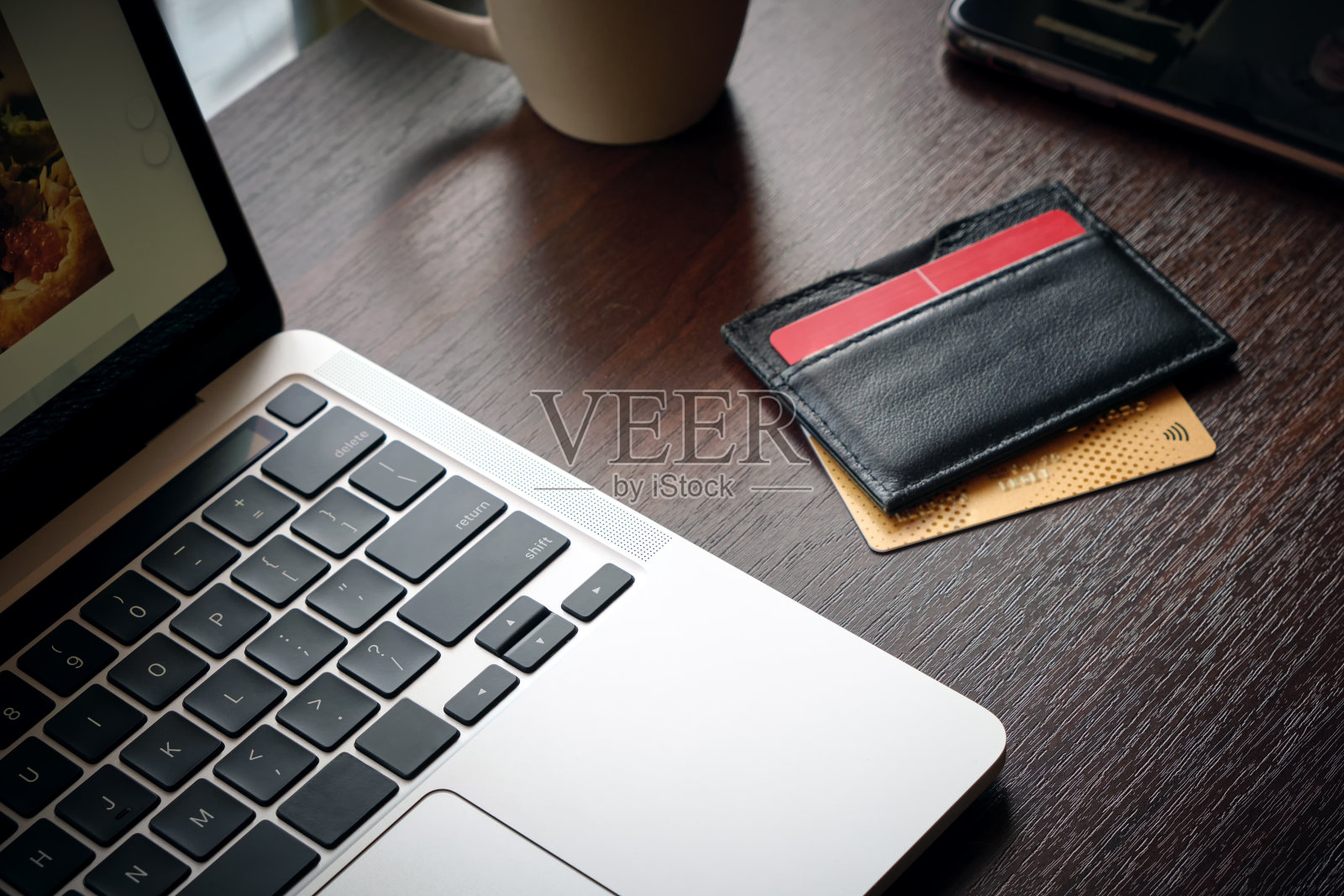 现代笔记本电脑、银行卡或信用卡、一杯咖啡和一部智能手机的特写。照片摄影图片