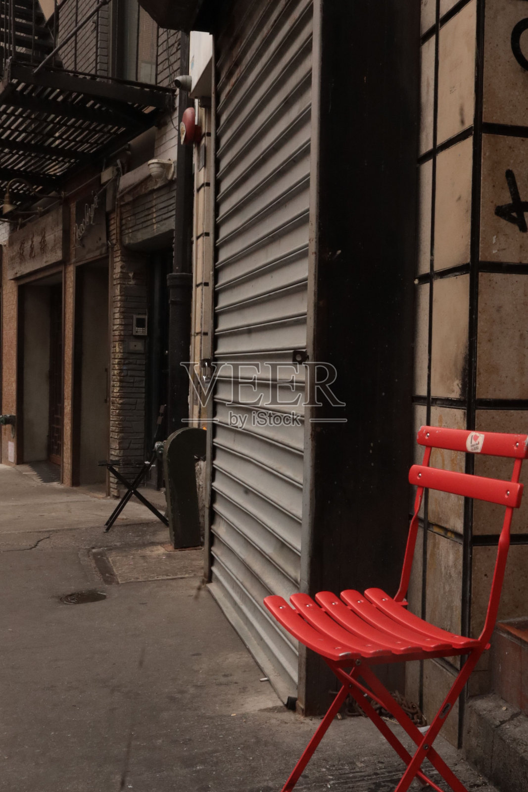 熙熙攘攘的城市街道人行道上的红椅子。照片摄影图片