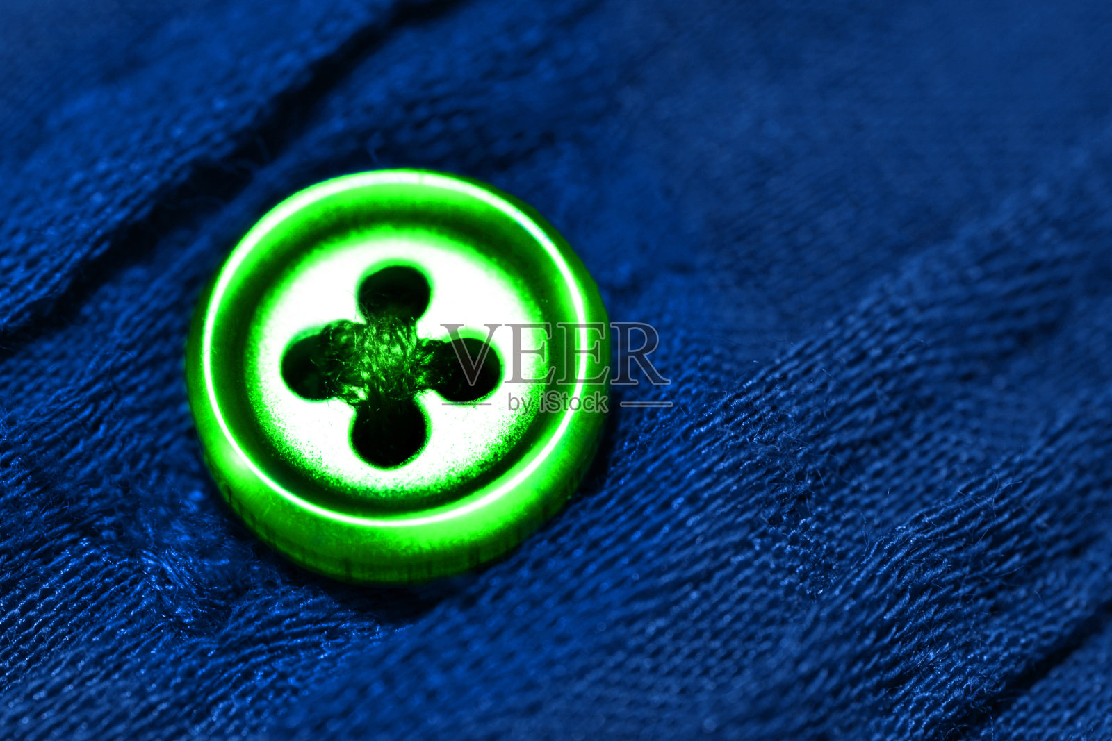 蓝色衬衫或布衣上的绿色纽扣，颜色对比时尚照片摄影图片