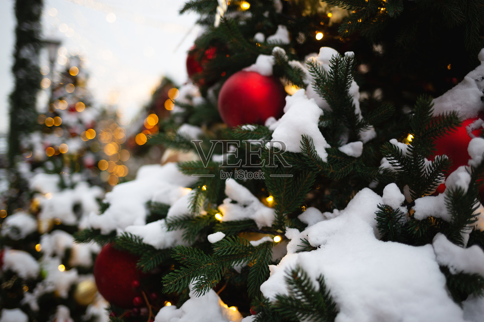 在灯光和雪的背景下，圣诞树上五颜六色的玩具照片摄影图片