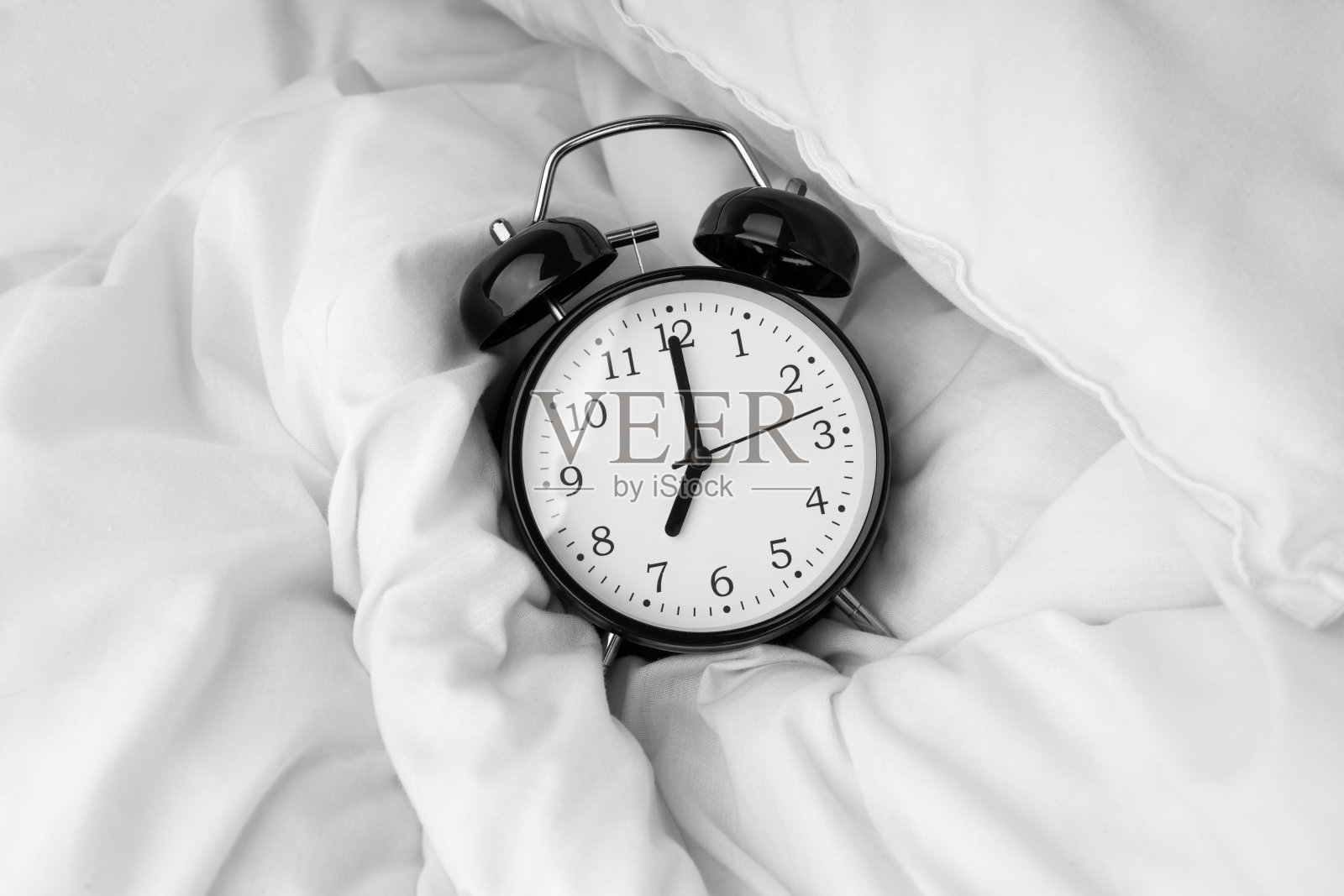 闹钟躺在白色的床上照片摄影图片