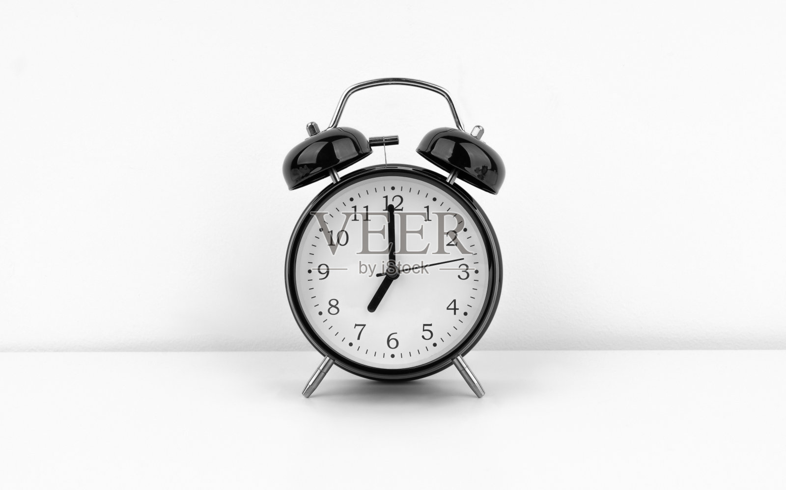 白色墙壁背景上的黑色闹钟照片摄影图片