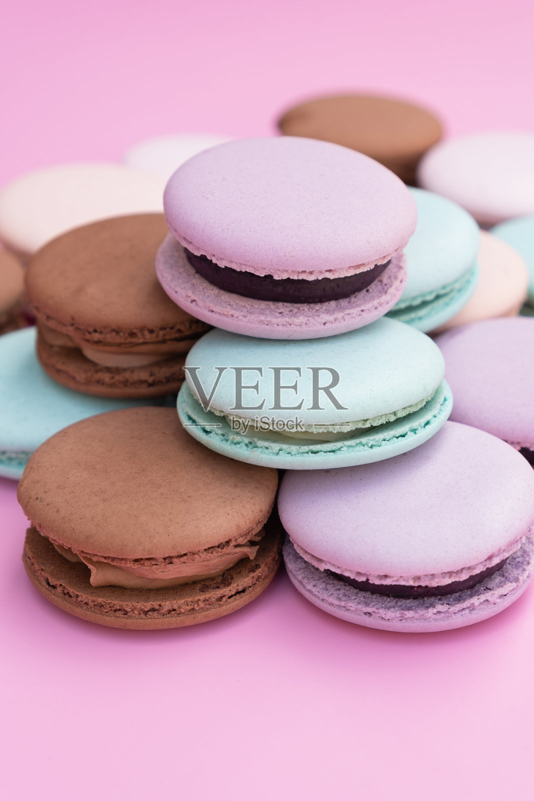 粉色背景上不同颜色的酥皮马卡龙照片摄影图片