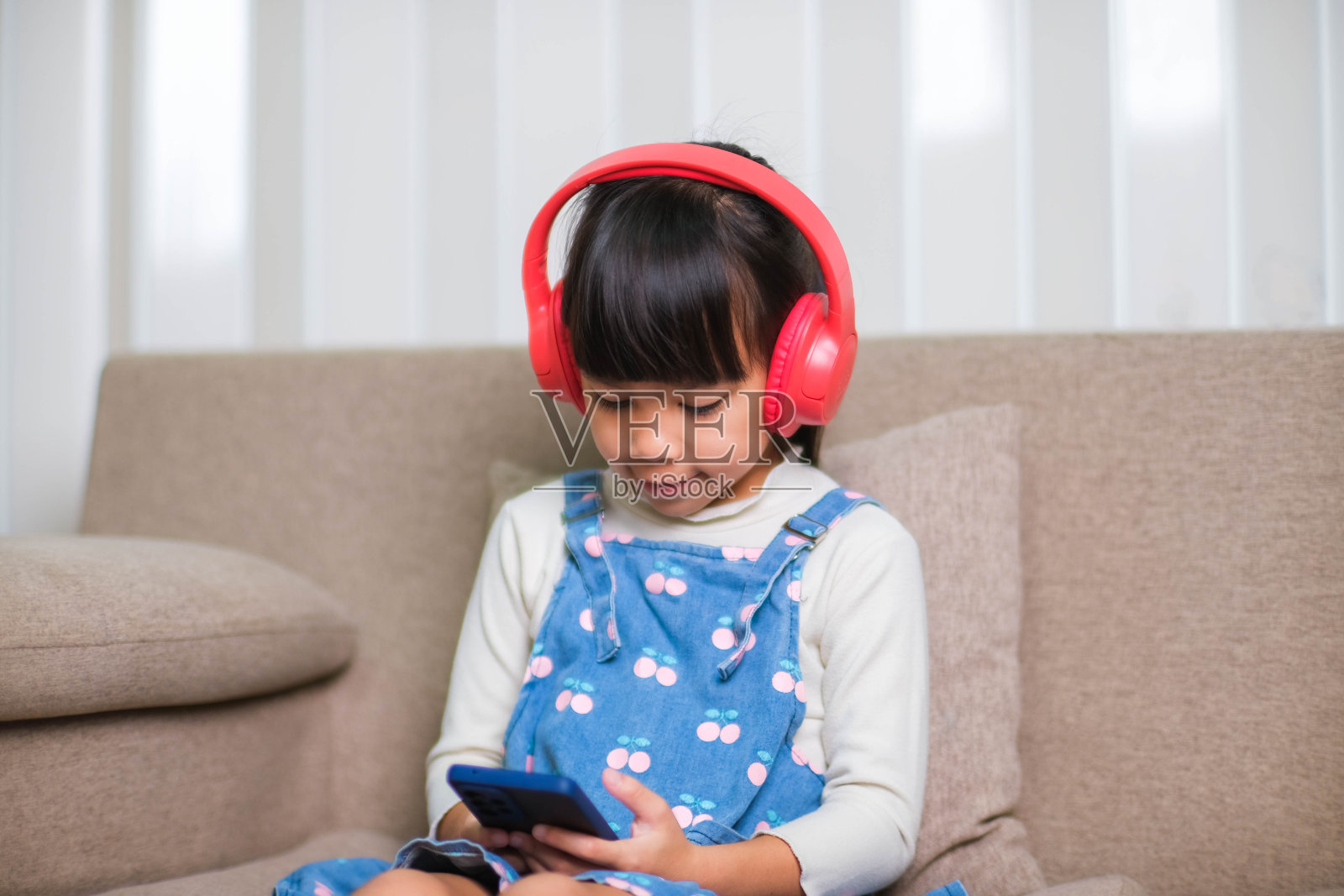 快乐的年轻女子，早上在家里醒来后，端着一杯咖啡，坐在沙发上看书。生活方式，自由时间和放松。照片摄影图片