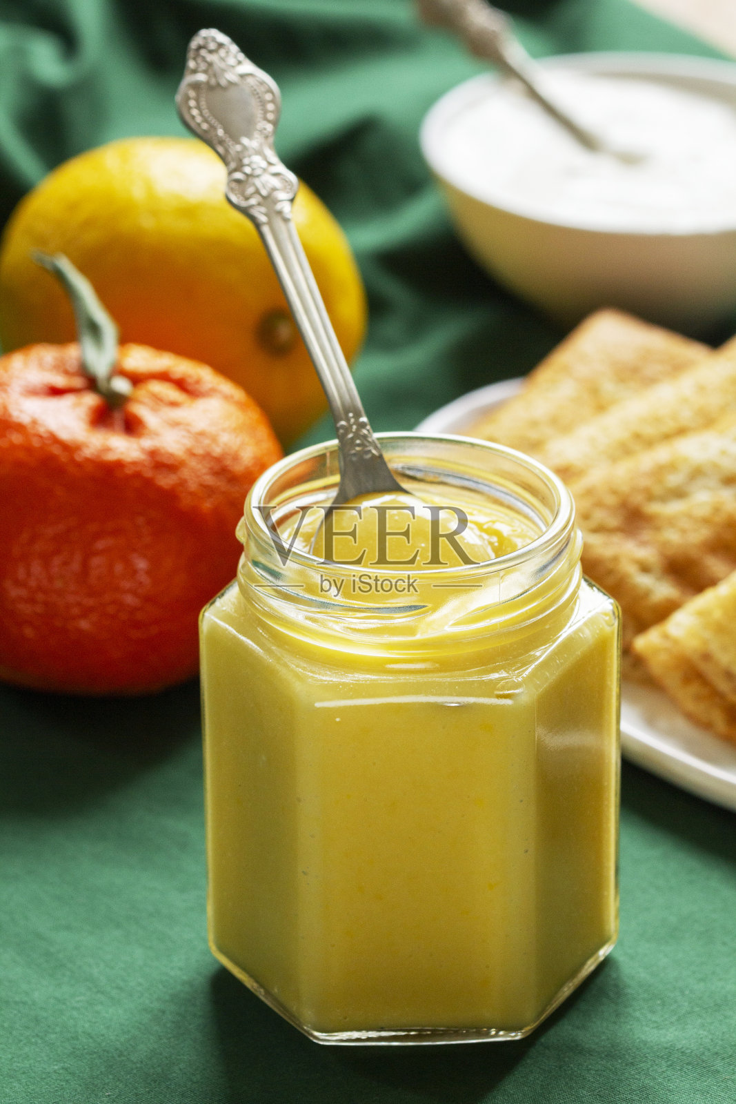 绿色背景上的柠檬、橘子、煎饼和酸奶油。乡村风格。照片摄影图片