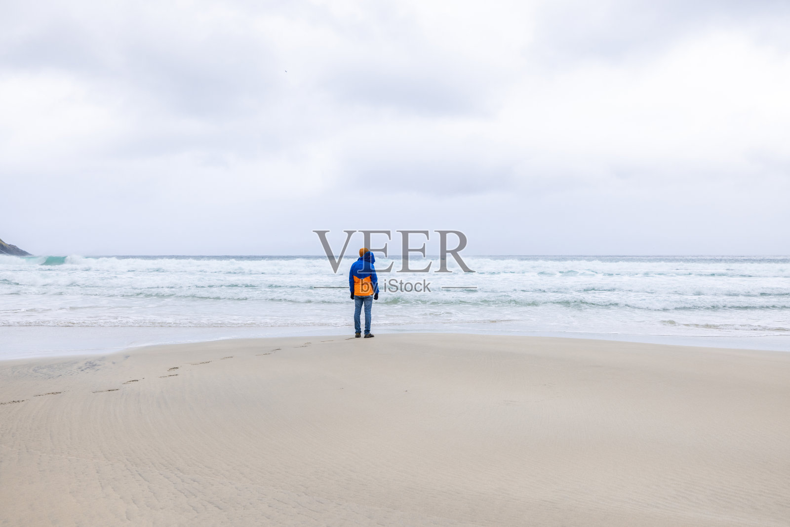 一个遥远的人站在挪威空旷的海滩上，望着大海照片摄影图片
