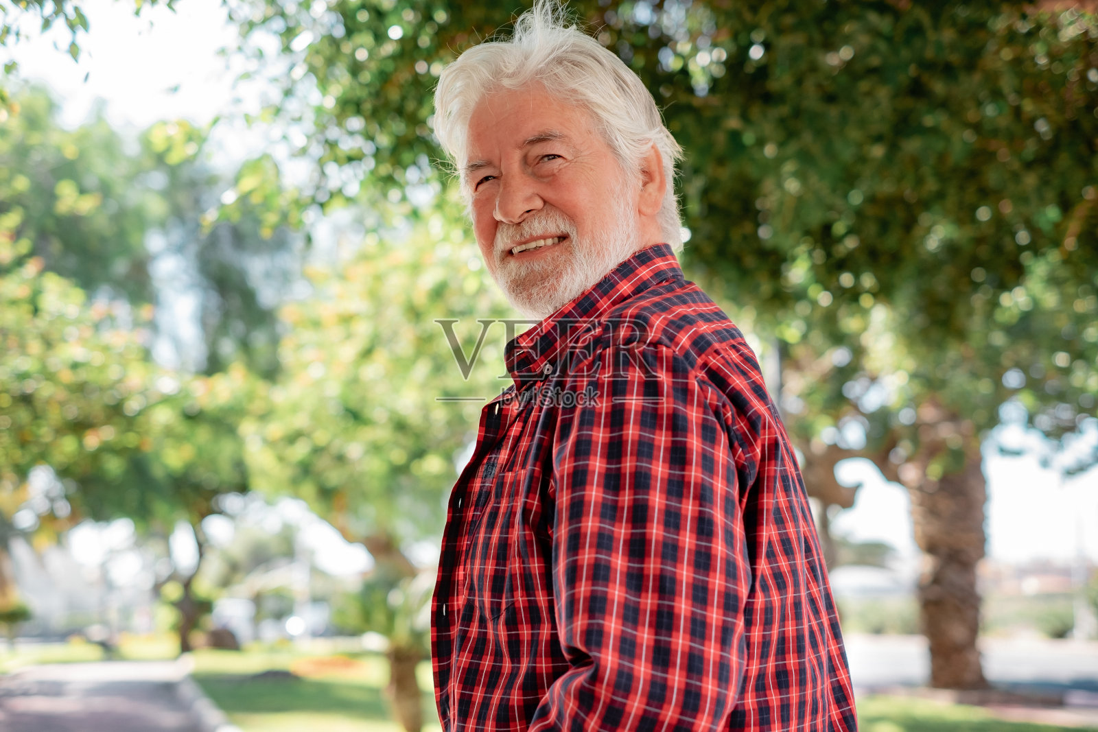 英俊的白发老人走在城市公园看着镜头微笑的肖像照片摄影图片