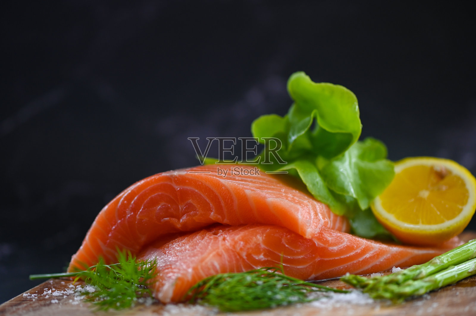 三文鱼里脊用柠檬、芦笋等香草和香料制成，新鲜的三文鱼生鱼片冰上煮食海鲜三文鱼照片摄影图片