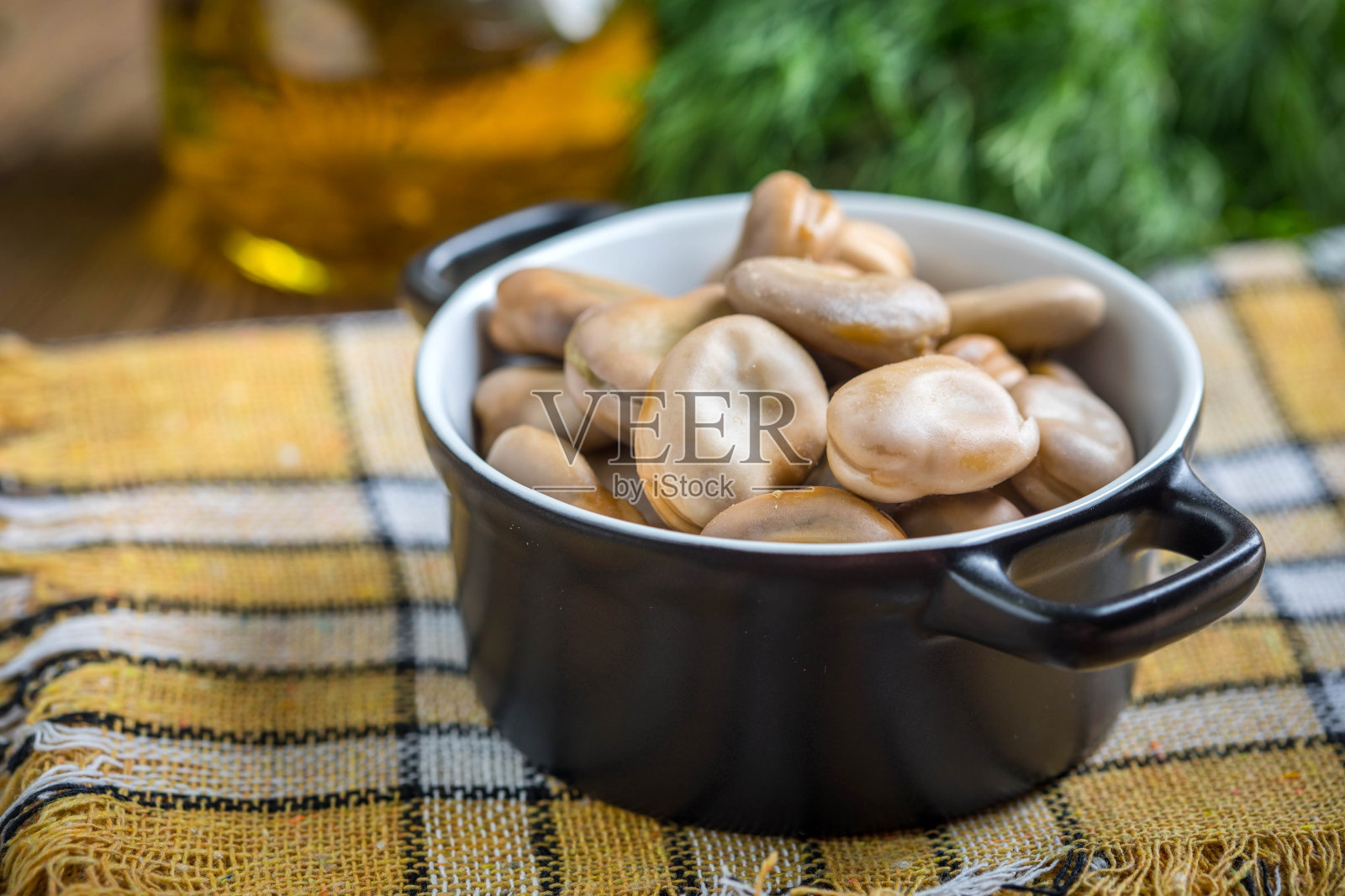 用黑碗盛蚕豆。照片摄影图片