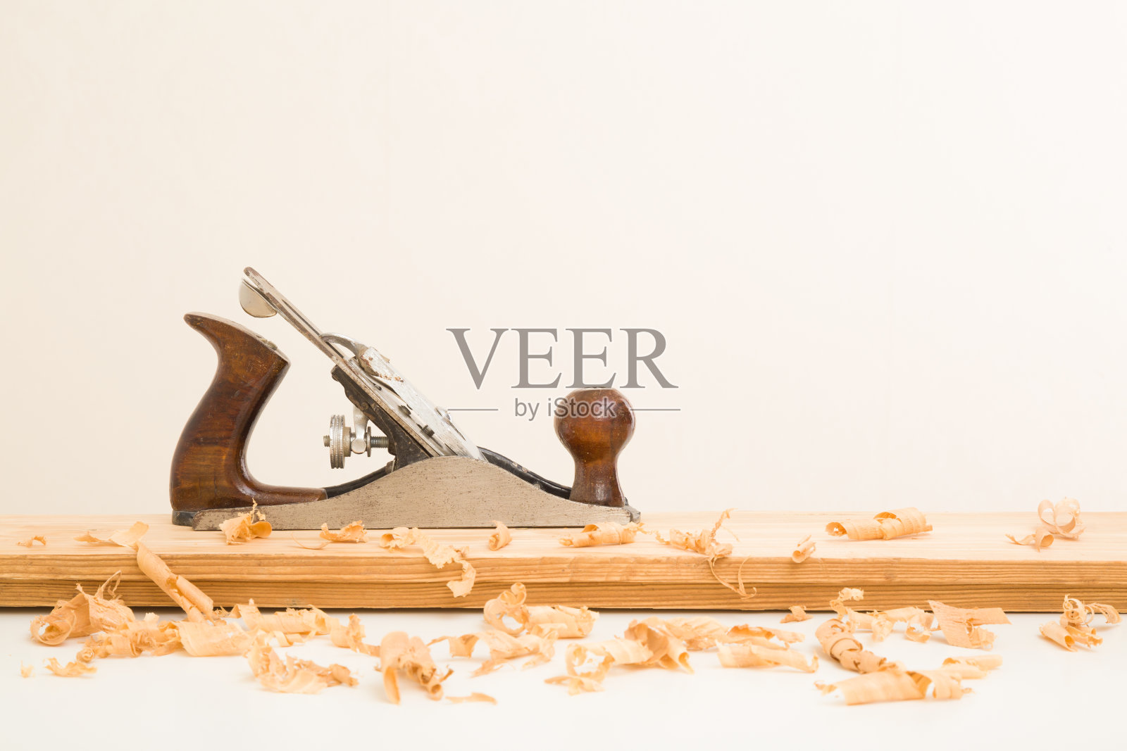 在浅灰色的墙壁背景下，白色桌子上的旧木板上手工拼接和刨花。特写镜头。为家里的维修工作准备材料。侧视图。照片摄影图片