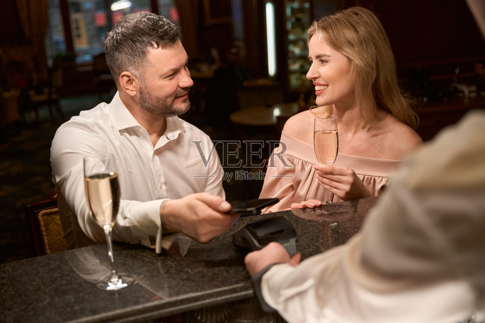 酒保拿着信用卡读卡器，情侣们在进行非接触式支付照片摄影图片