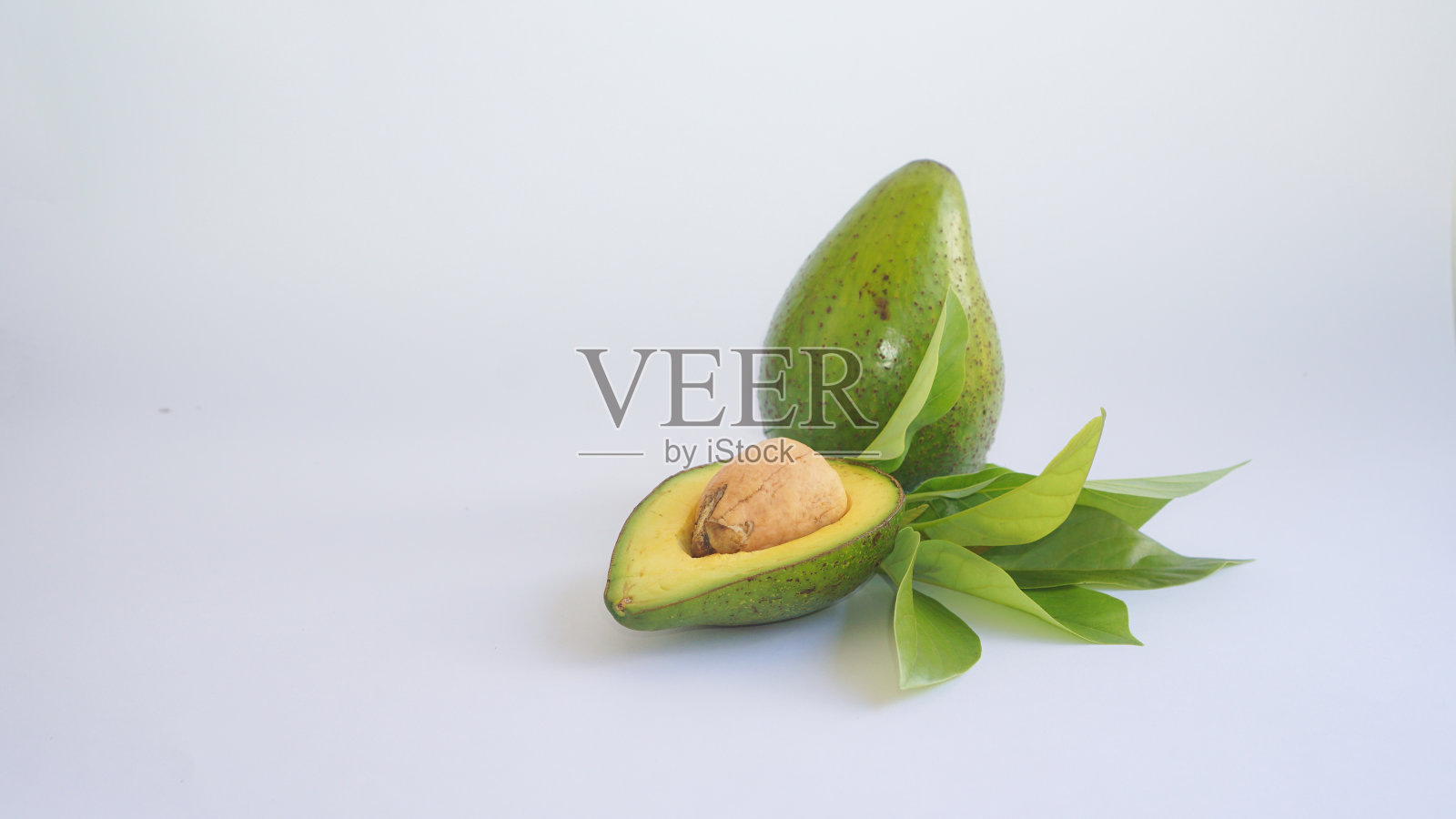 一组成熟的鳄梨由半个鳄梨、种子、整个鳄梨和叶子组成照片摄影图片
