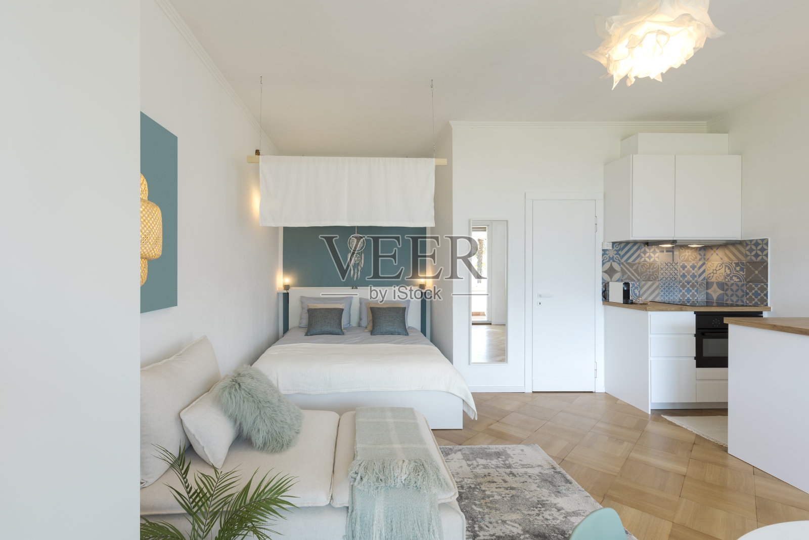 一室公寓，一张双人床和一张单人床。还有拼花地板，一盏灯和一个漂亮的天篷。照片摄影图片