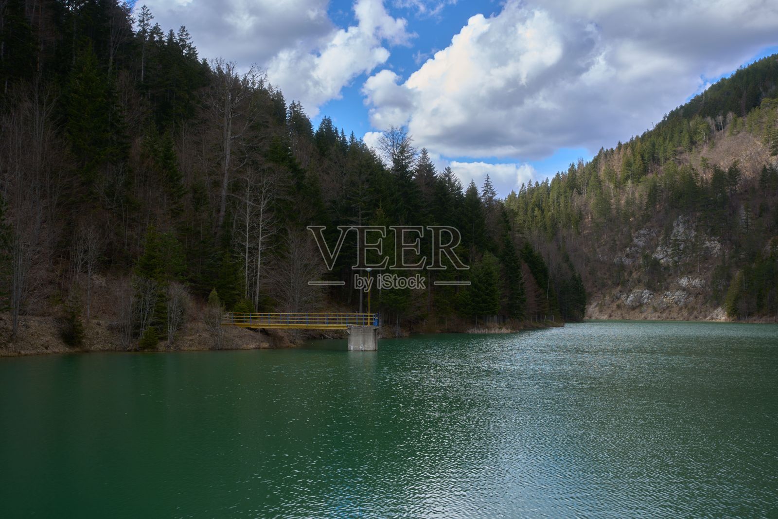 宁静的湖泊四周环绕着常绿树木覆盖的山脉。照片摄影图片