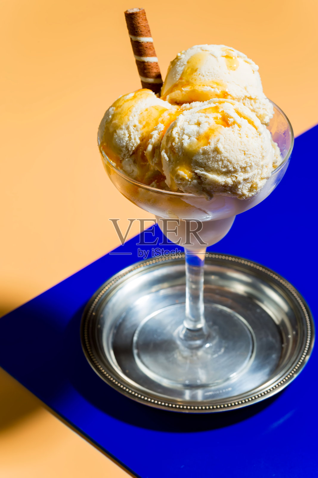 玻璃杯里装着冰淇淋，背景颜色鲜艳。照片摄影图片