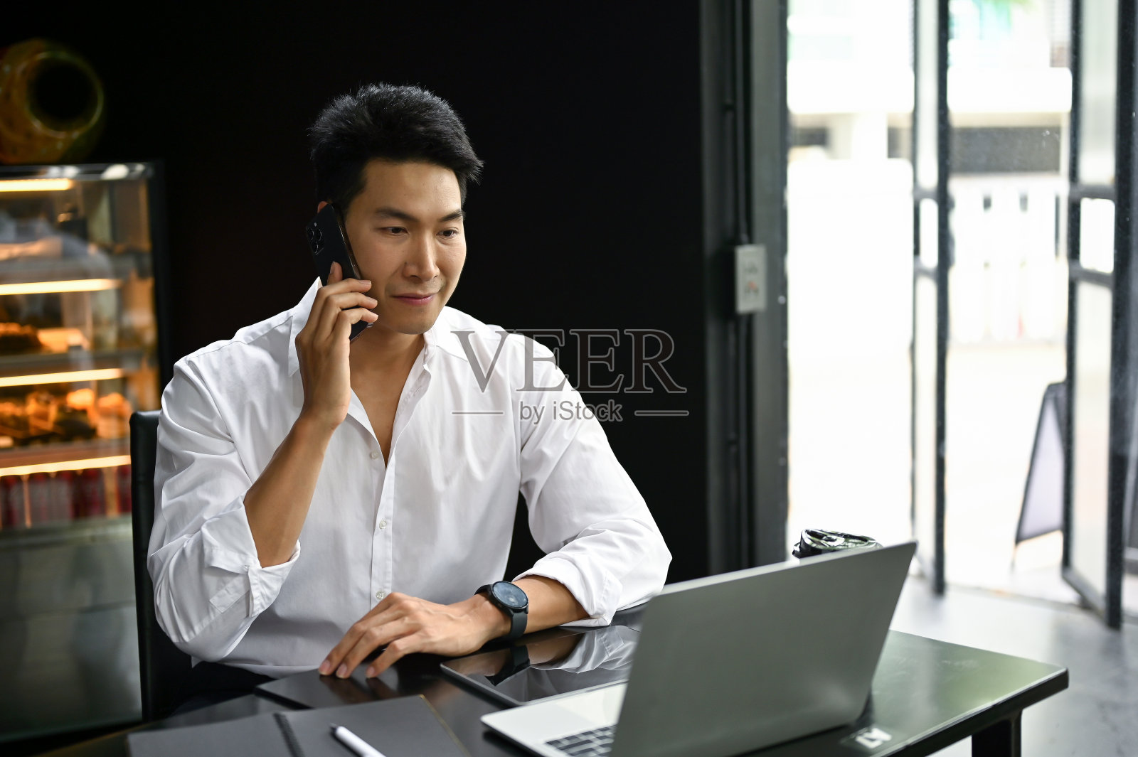 一位亚洲商人在咖啡馆里与他的商业客户通电话。照片摄影图片