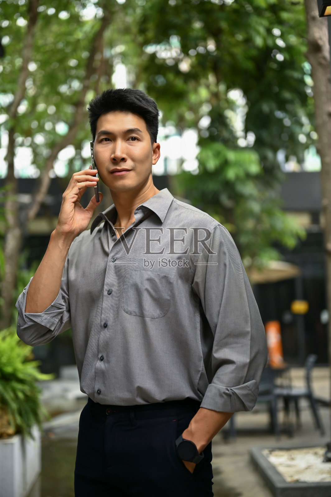 一个男人站在大楼外面和别人讲电话。照片摄影图片