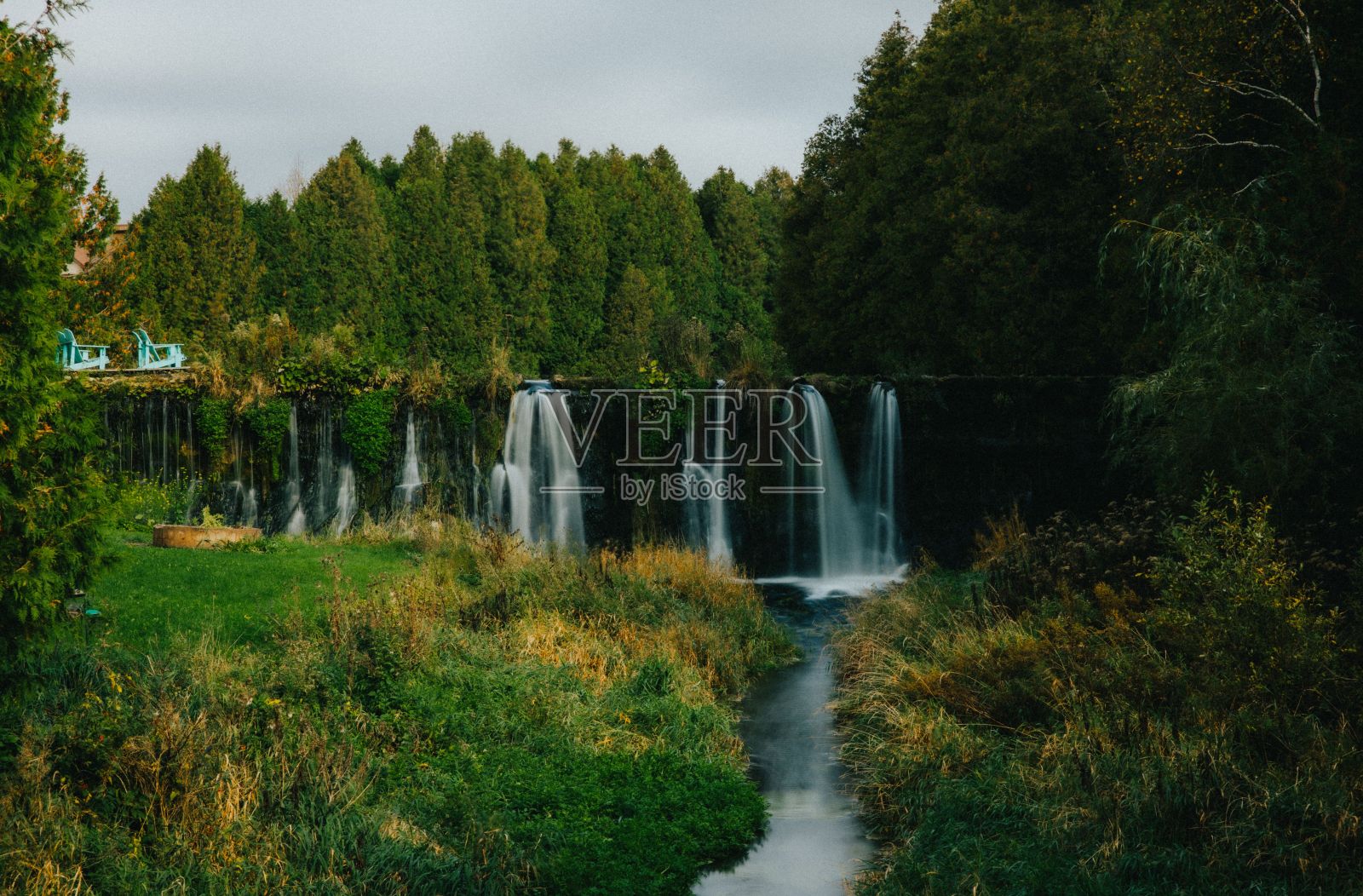 郁郁葱葱的绿色植被和瀑布倾泻而下的宁静河流景观照片摄影图片