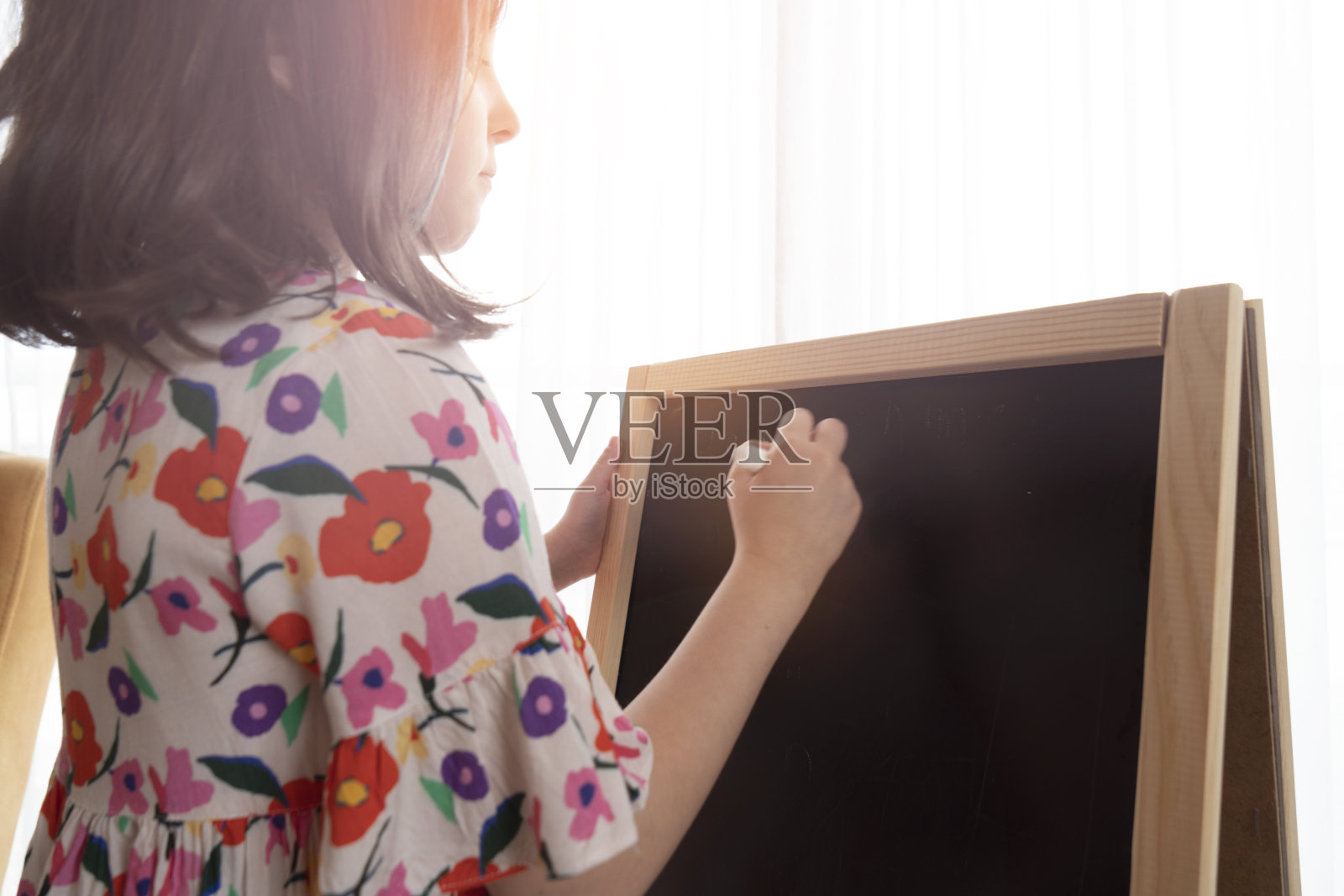 小女孩在黑板上写字照片摄影图片