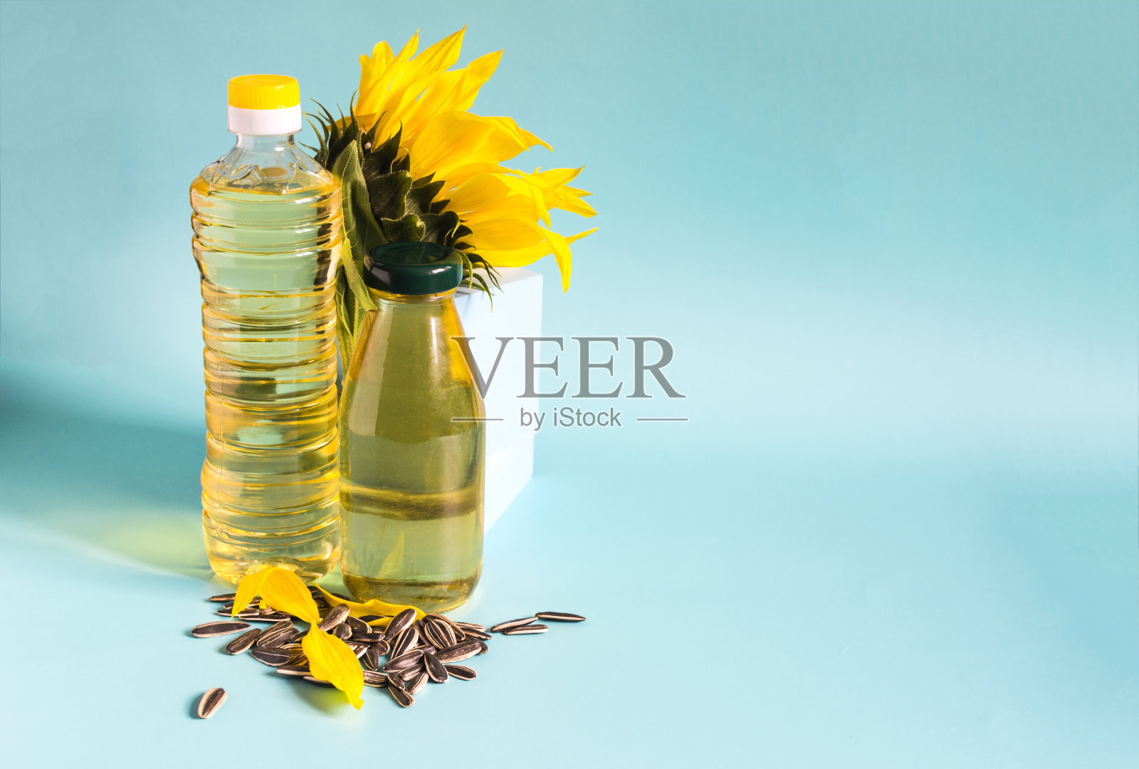 葵花籽油在透明的瓶子和装饰的葵花籽和葵花花在一个蓝色的背景复制空间照片摄影图片