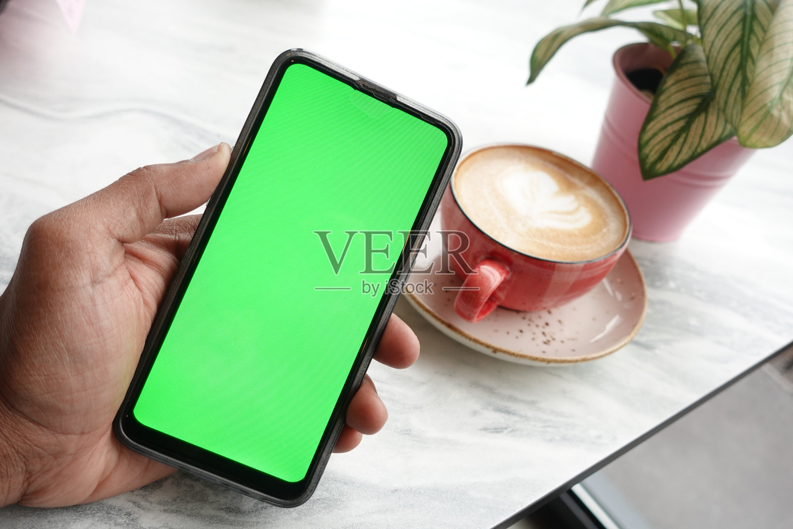 拿着咖啡CPU，用绿屏智能手机照片摄影图片