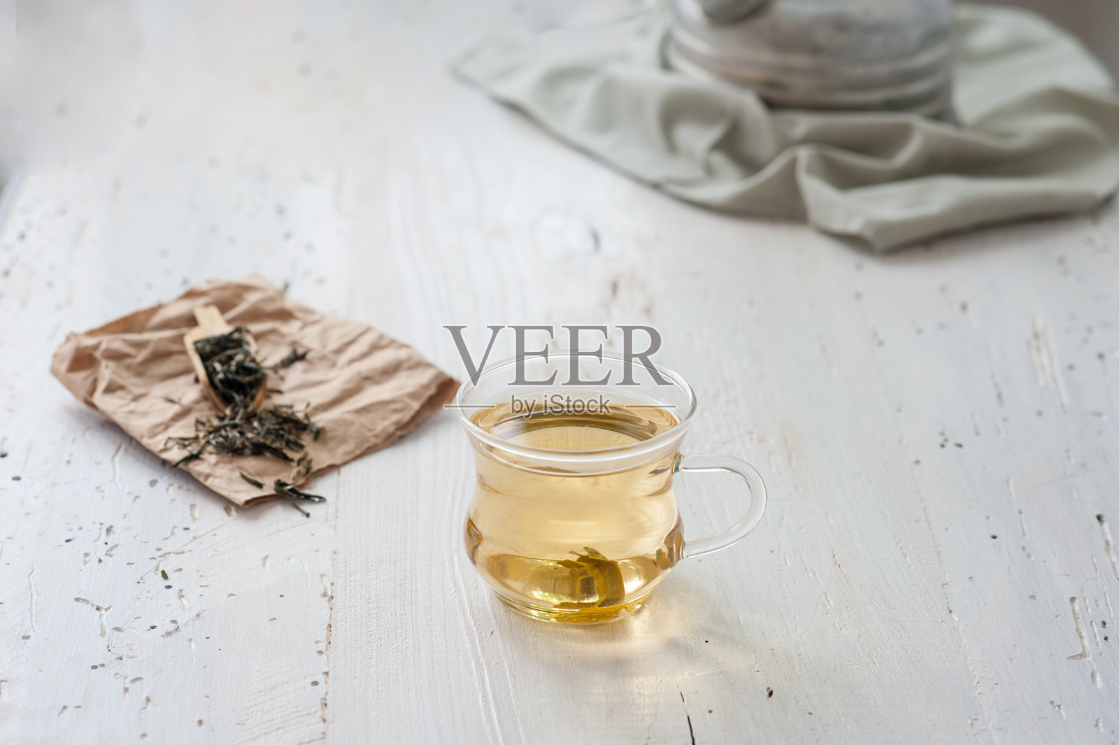 刚泡好的白茶放在风化的木板上，背景是复古的茶壶照片摄影图片