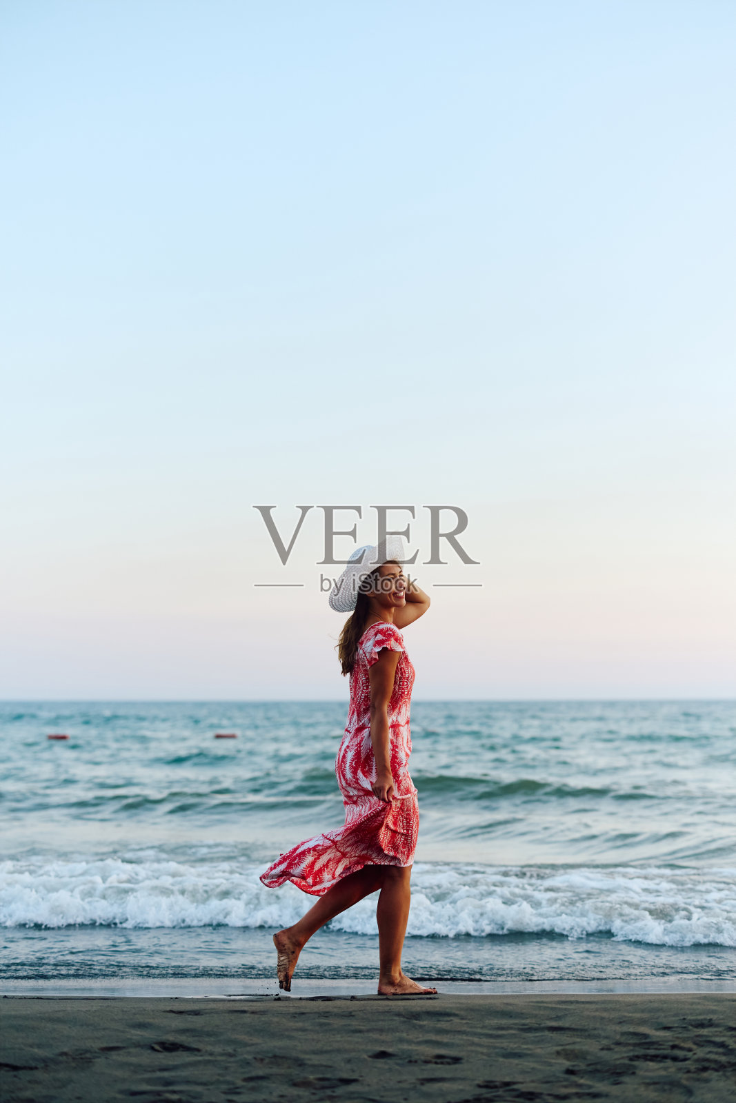 一个无忧无虑的年轻女子在夏日的沙滩上散步。照片摄影图片