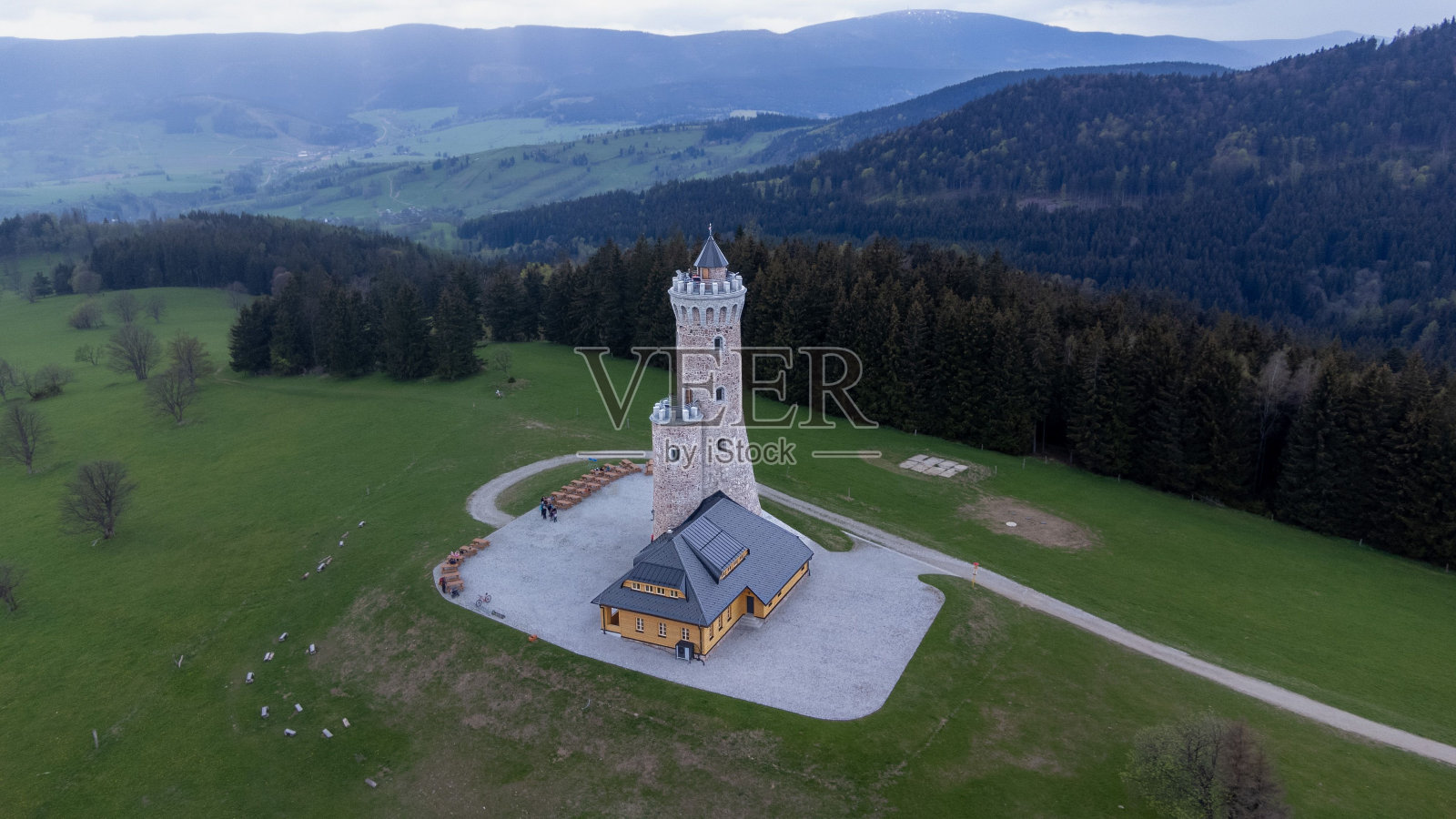 在阴天的绿色山坡上鸟瞰一座石塔照片摄影图片