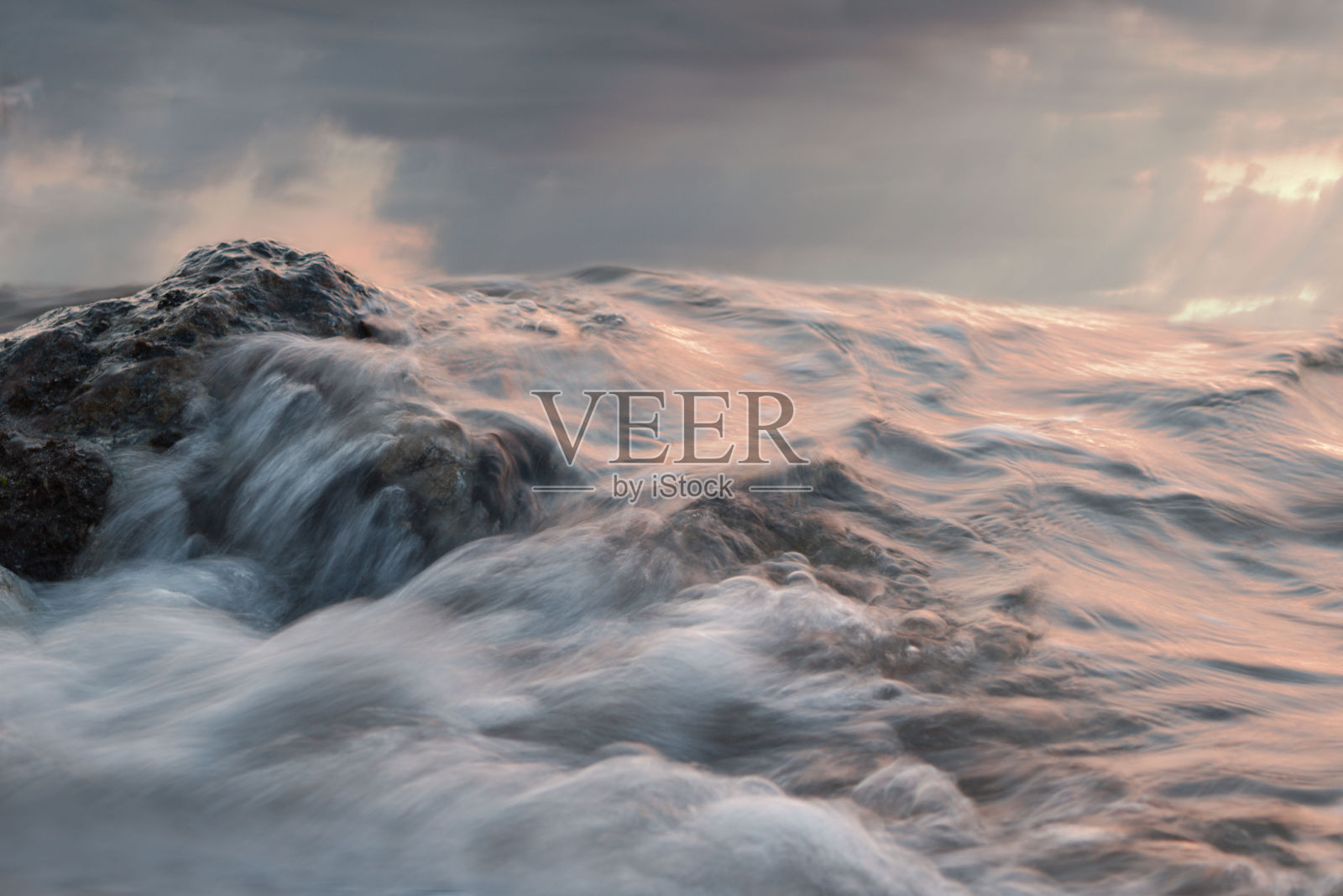 暴风雨的海水掠过岩石，温暖的色调照片摄影图片