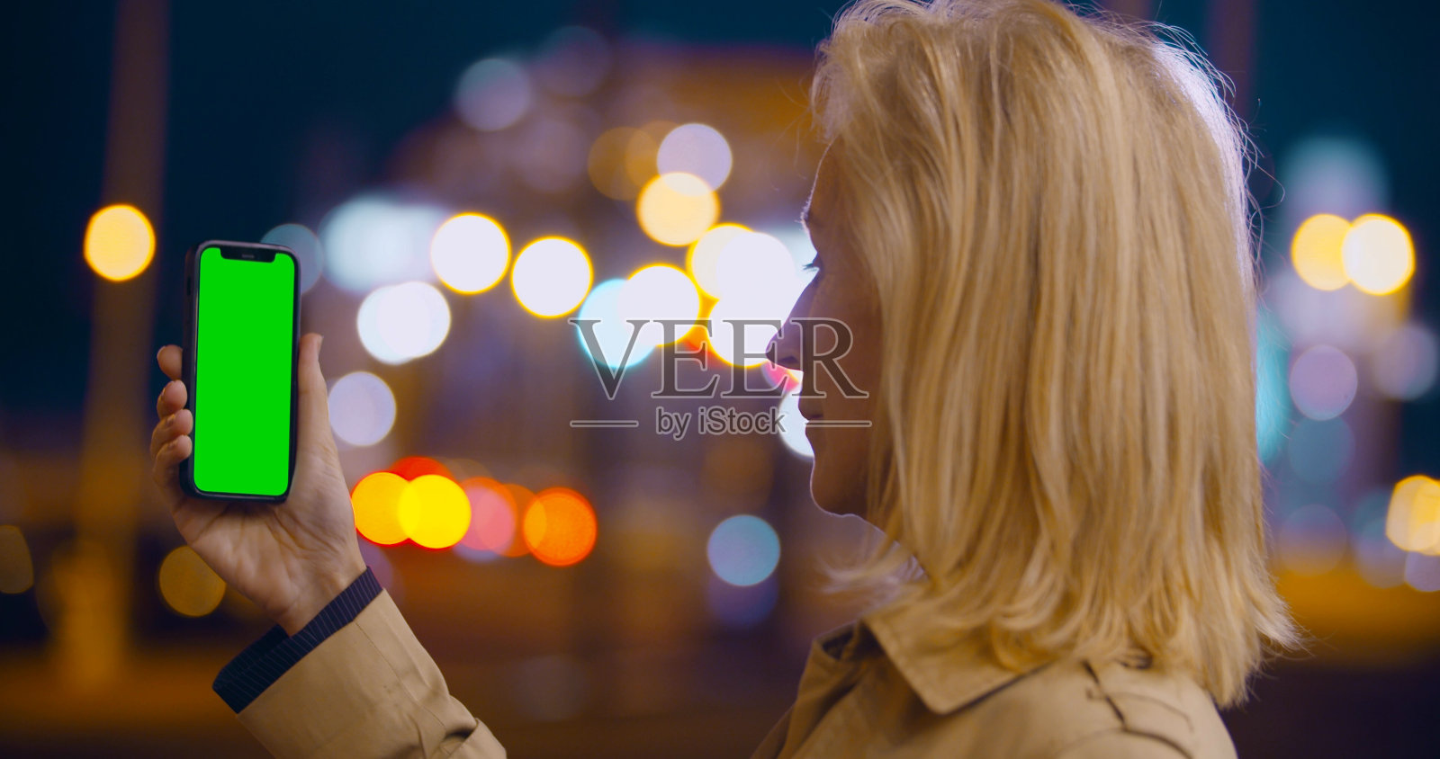 老年妇女手持绿色空白屏幕的智能手机在户外拍摄的散景照片照片摄影图片