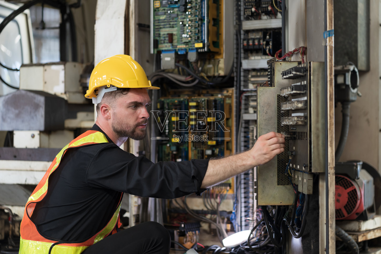 在工厂检查、修理、维护数控机床的电气系统。男性电工工程师在制造过程中检查质量电气照片摄影图片