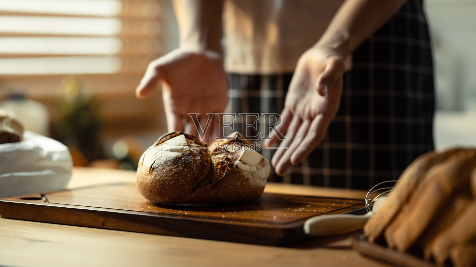 在案板上烤着酸面包，男面包师站在后面。健康饮食，烘焙糕点理念。照片摄影图片