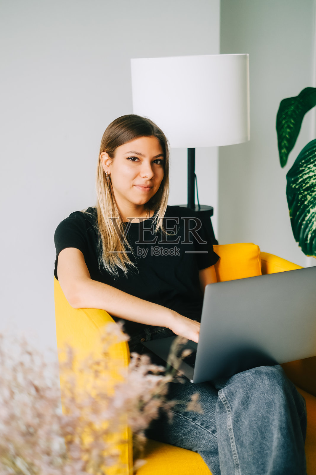 美丽的年轻微笑白人妇女休息在沙发上，使用笔记本电脑。和朋友聊天，浏览信息照片摄影图片