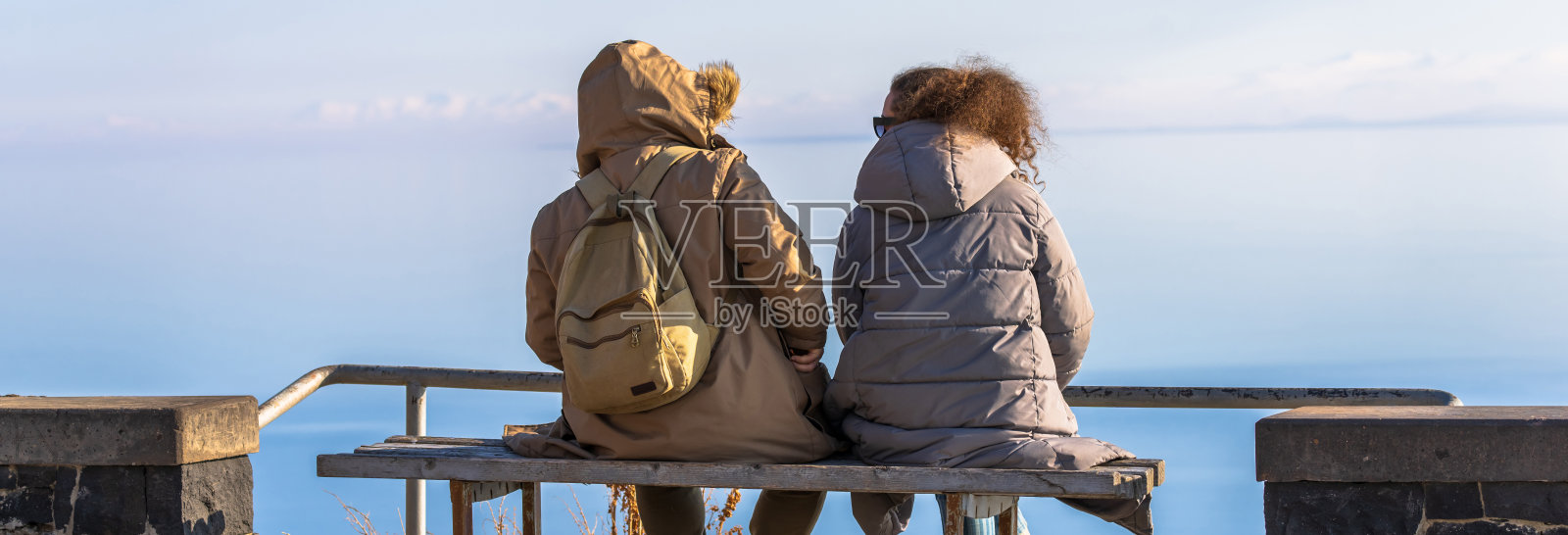 人们坐在湖边的长凳上照片摄影图片