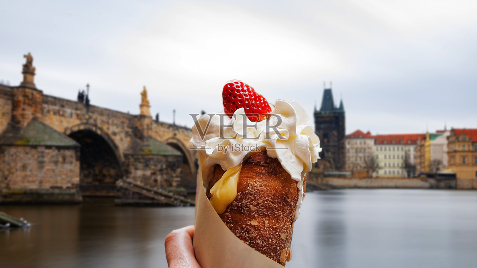 加了奶油和草莓的trdelnik，布拉格的查理大桥风景。典型的地方美食照片摄影图片