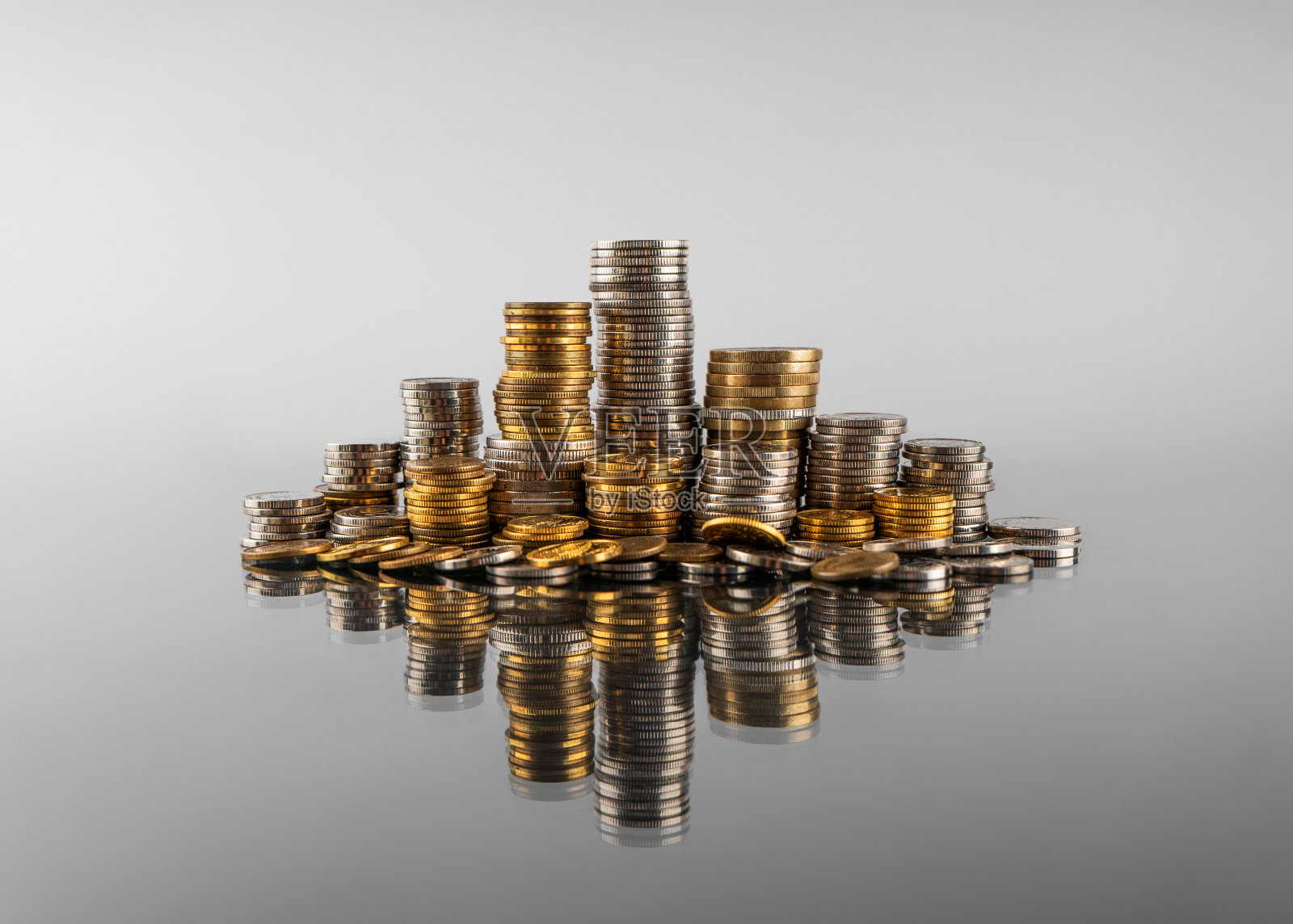 一堆堆硬币在灰色背景上的倒影照片摄影图片