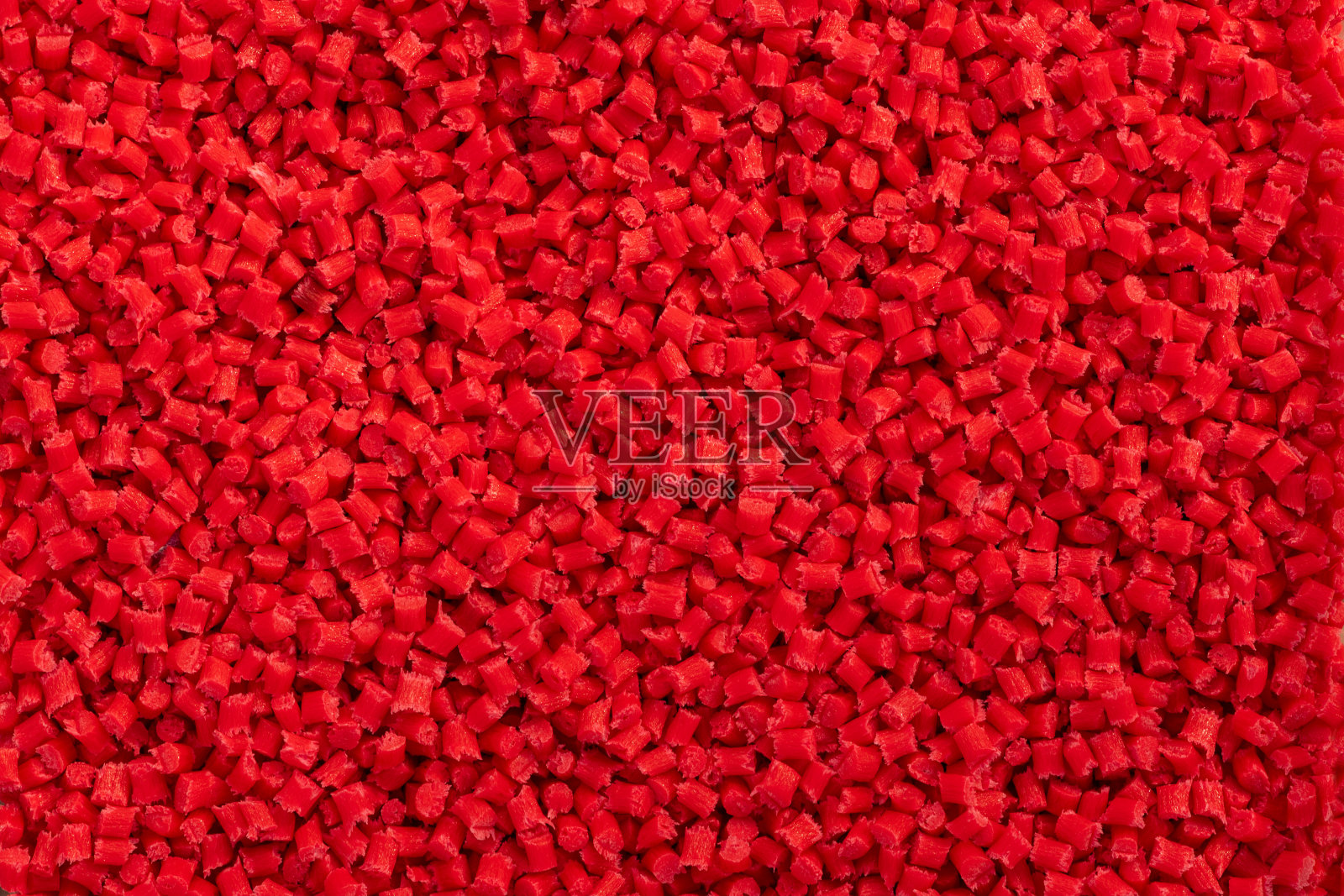 红色塑料树脂(母粒)铺在托盘上的特写照片摄影图片