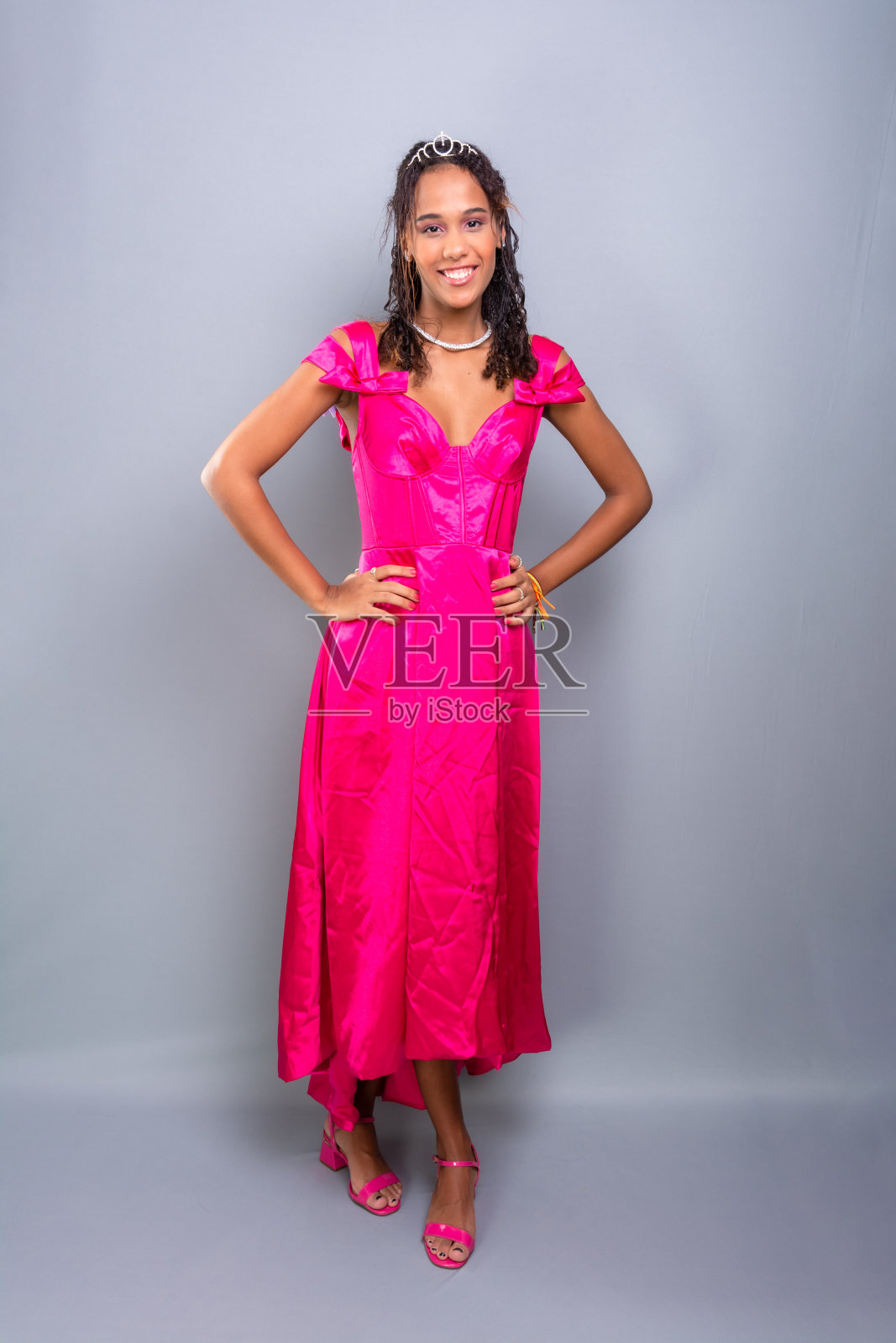 十几岁的女孩，漂亮，快乐，穿着粉红色的连衣裙站在那里。照片摄影图片