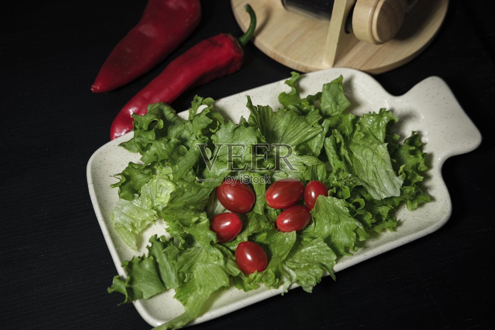 新鲜的绿色生菜叶和小红色樱桃鸡尾酒番茄在黑色木制背景照片摄影图片