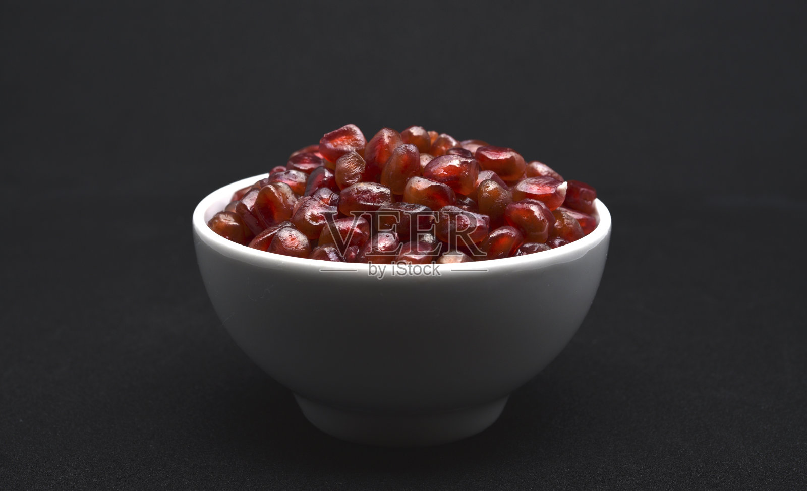 用陶瓷碗盛石榴。石榴果粒。照片摄影图片