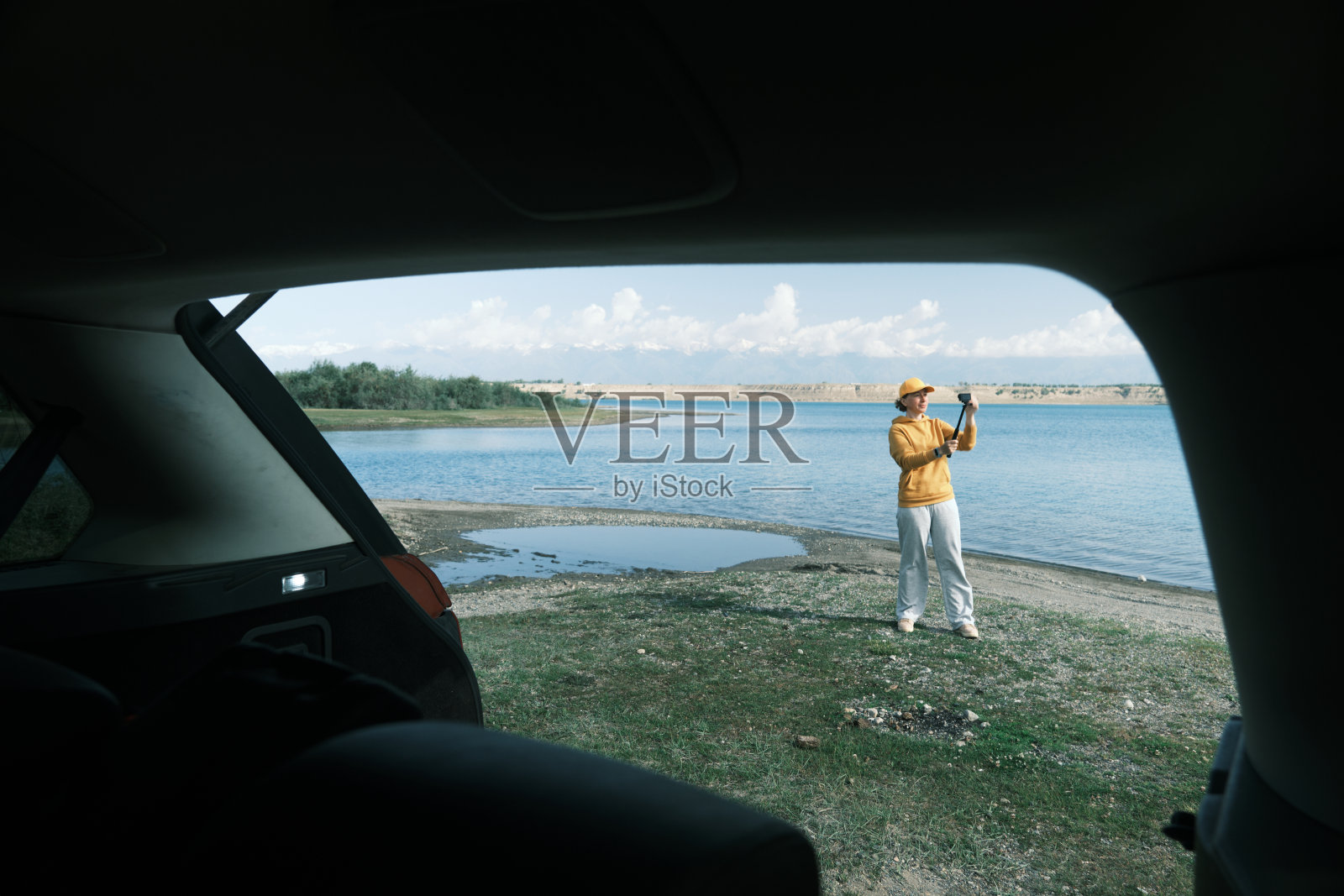 女人站在车旁边，在湖边流着水照片摄影图片