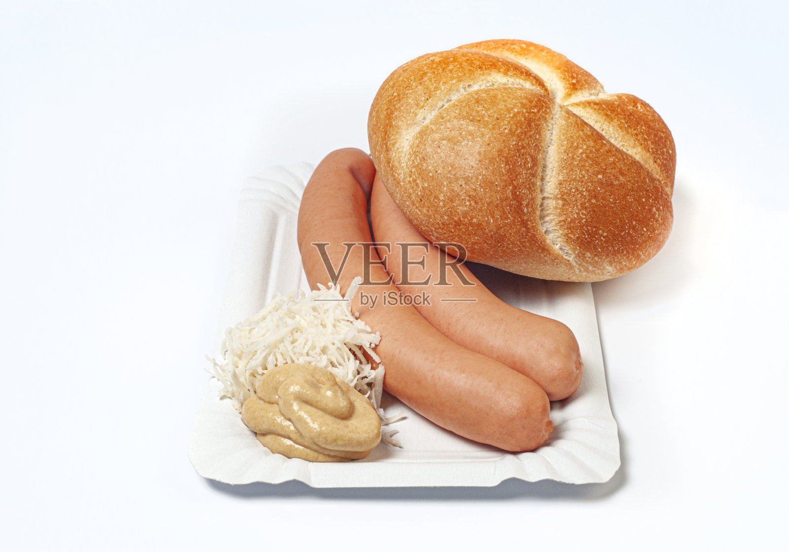 典型的奥地利小吃。一对法兰克福香肠放在纸盘里，配上新鲜磨碎的辣根、一团辣芥末和一个面包卷。照片摄影图片