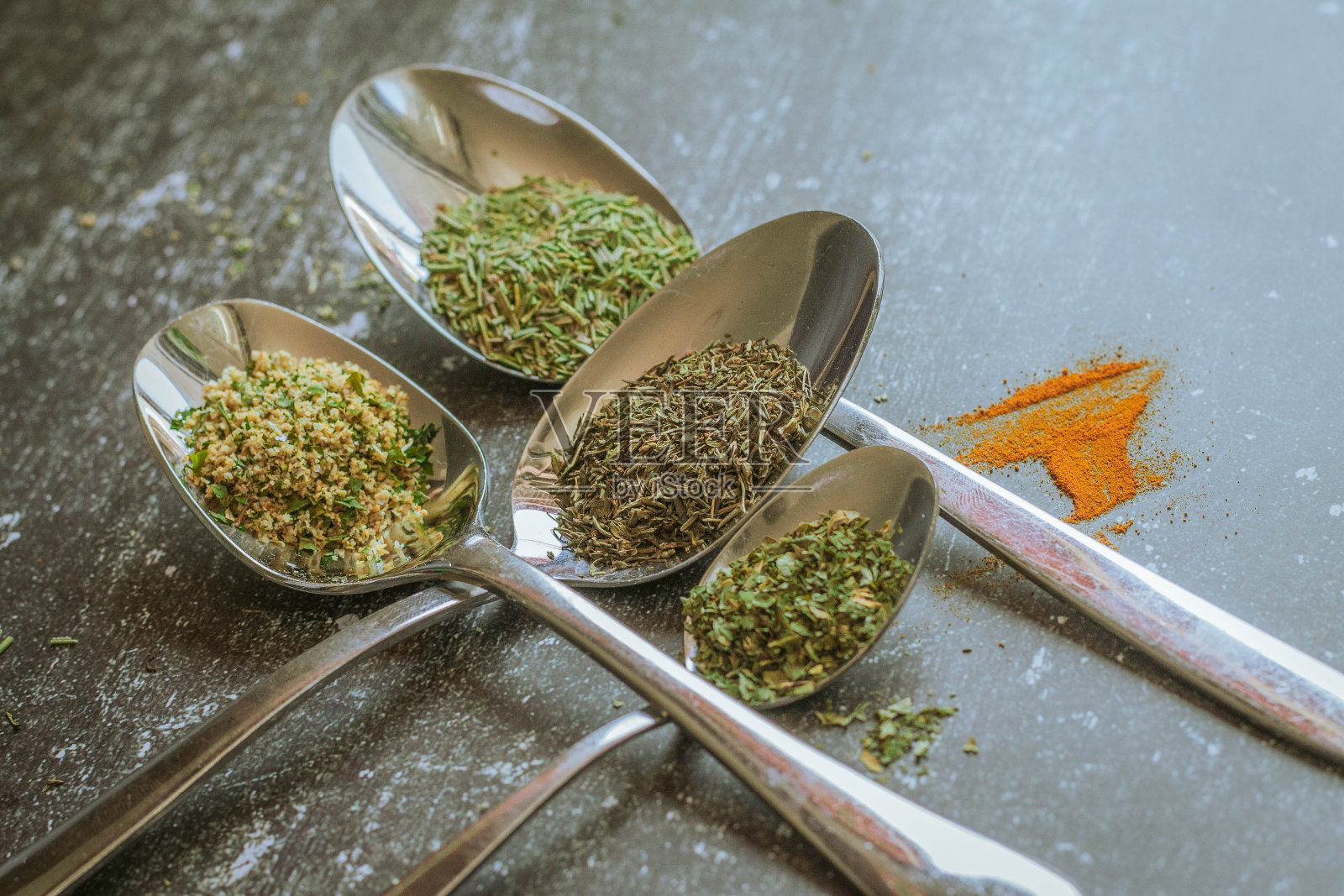 黑色背景上盛有香料和香草的勺子。食品和烹饪材料。照片摄影图片