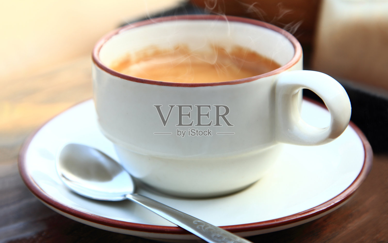 白色的咖啡杯里装着热饮在早晨的气氛中，拉近杯子里的咖啡和勺子放在茶托上照片摄影图片