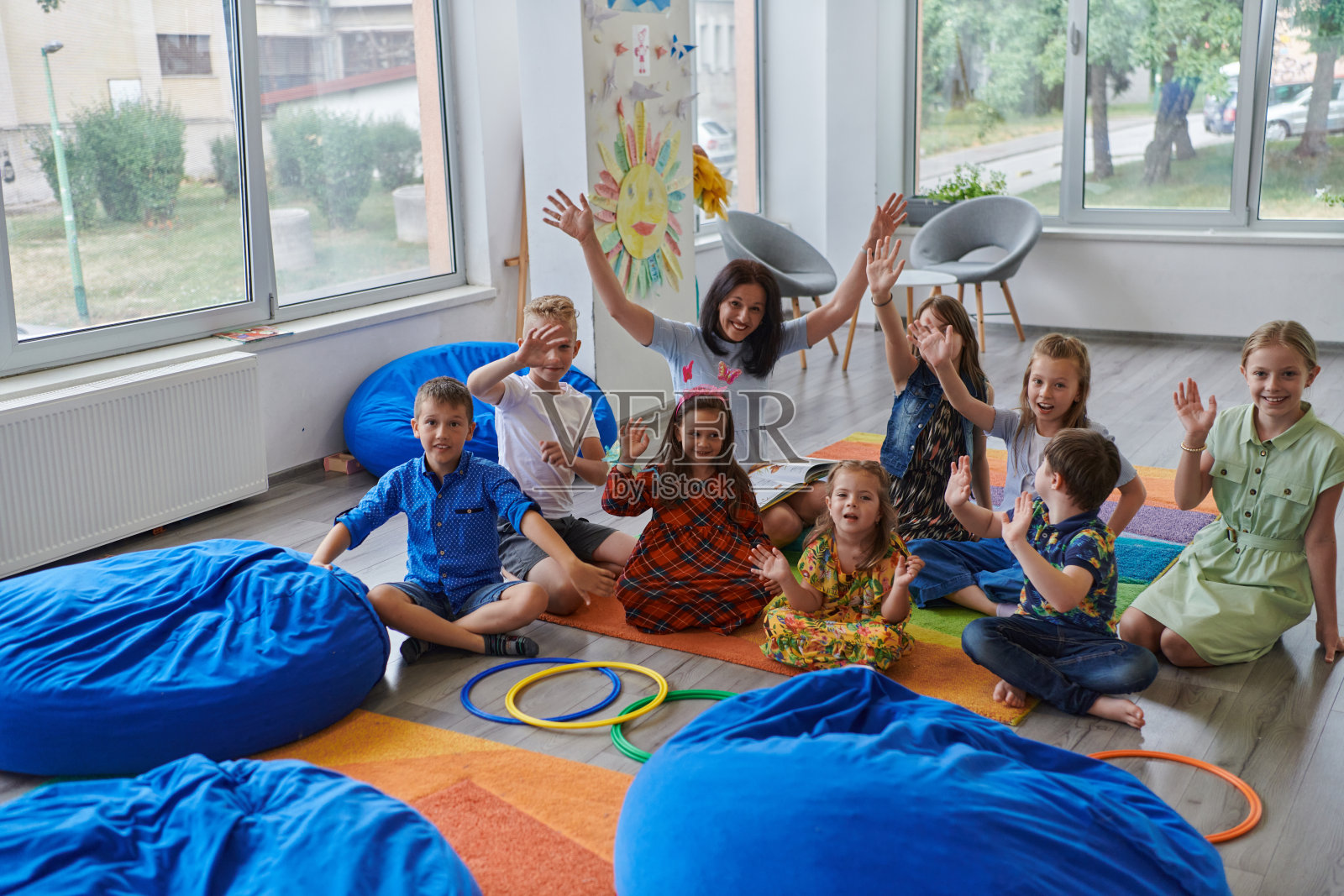 一位快乐的女老师和一群小学生坐在一起玩手游照片摄影图片