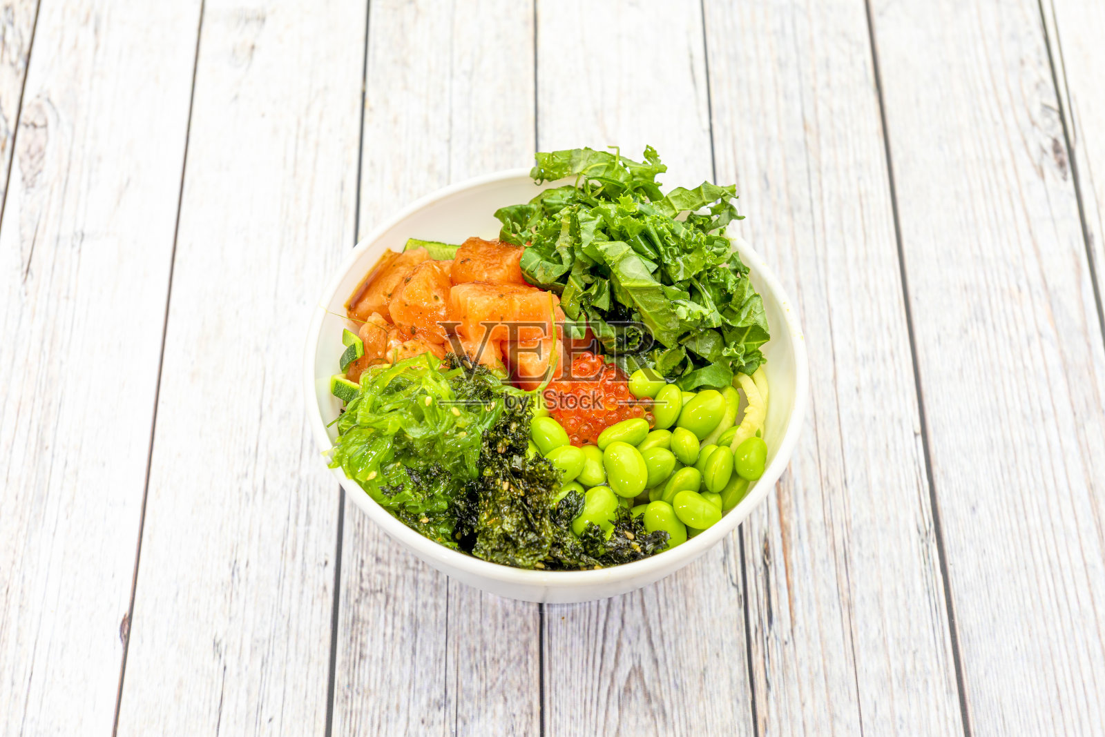 挪威三文鱼碗配鱼子、裙带菜、甘蓝碎、毛豆和西葫芦碎。照片摄影图片