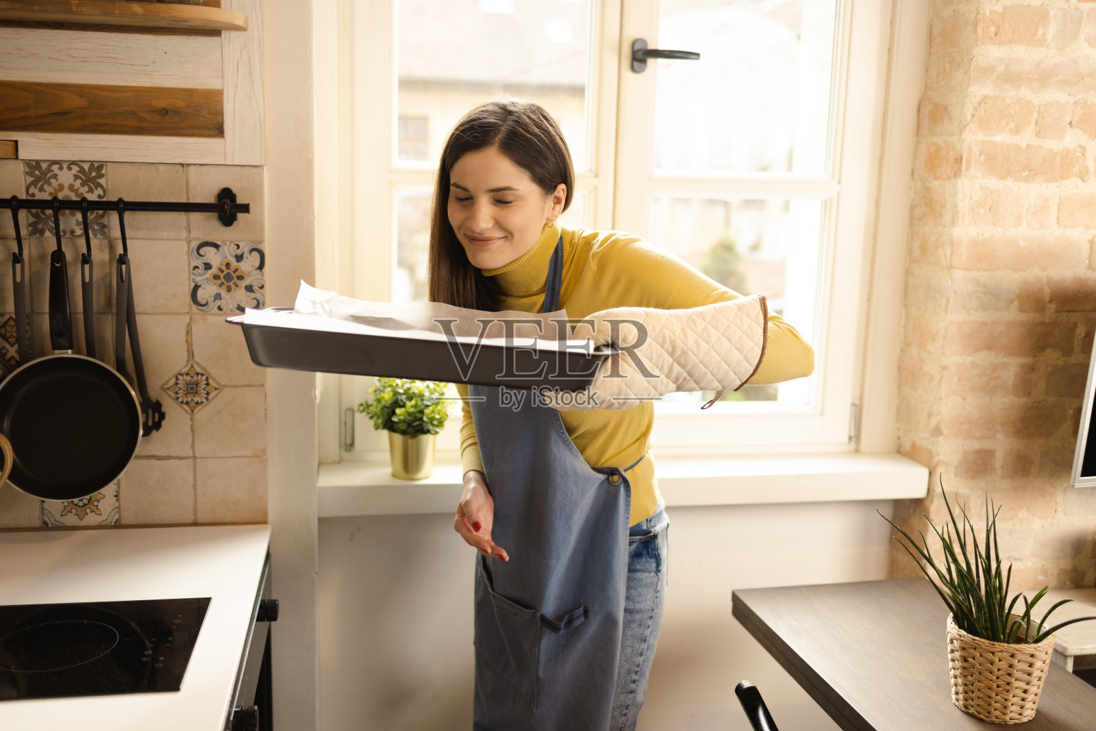 快乐的年轻女人从烤箱里取出热饼干照片摄影图片